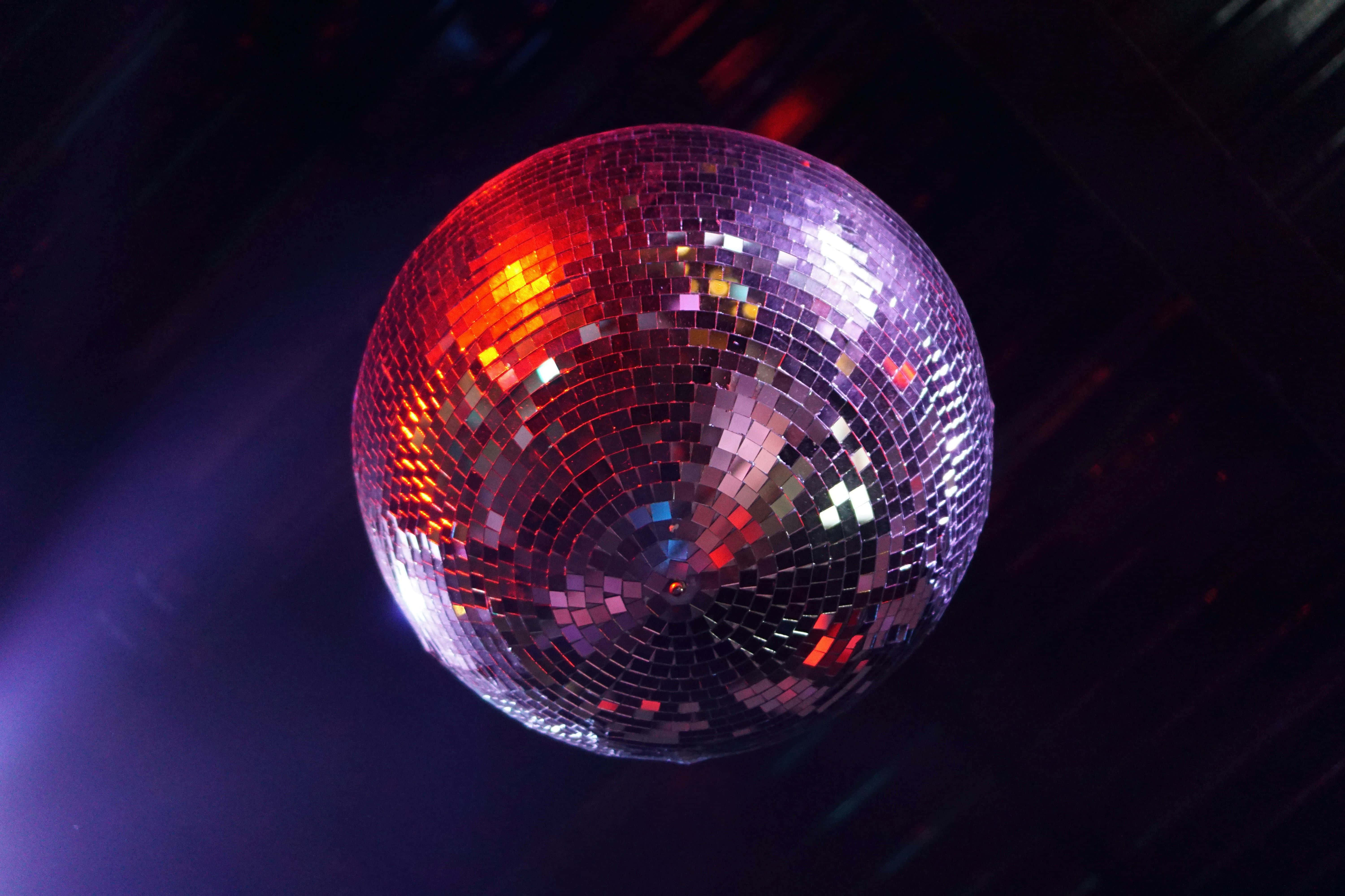 glowing disco ball, vibrant red and purple lights, dark club backdrop, 5K Desktop Wallpaper