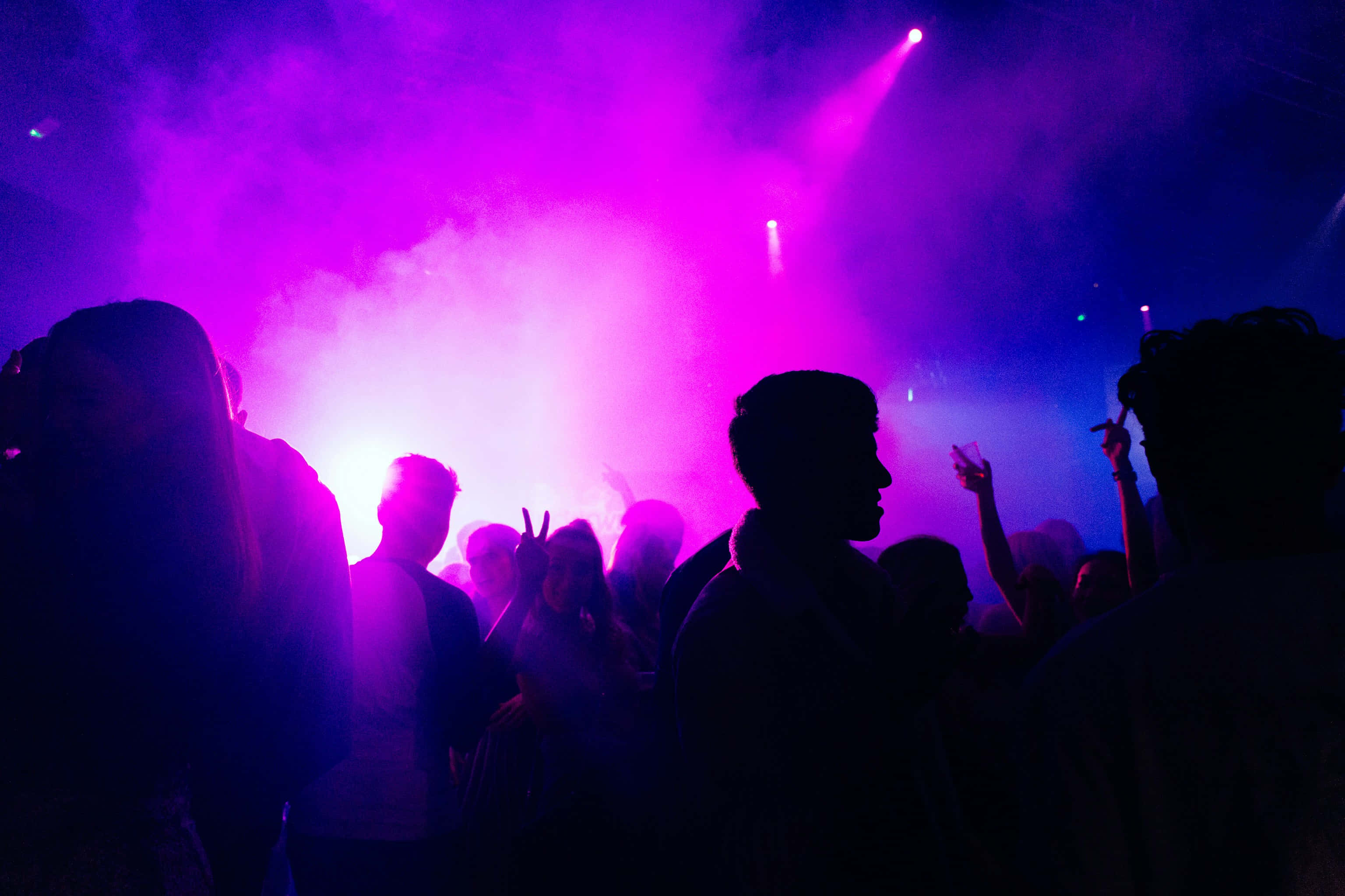vibrant purple stage lights, smoky nightclub atmosphere, silhouetted crowd dancing, 2K Desktop Wallpaper
