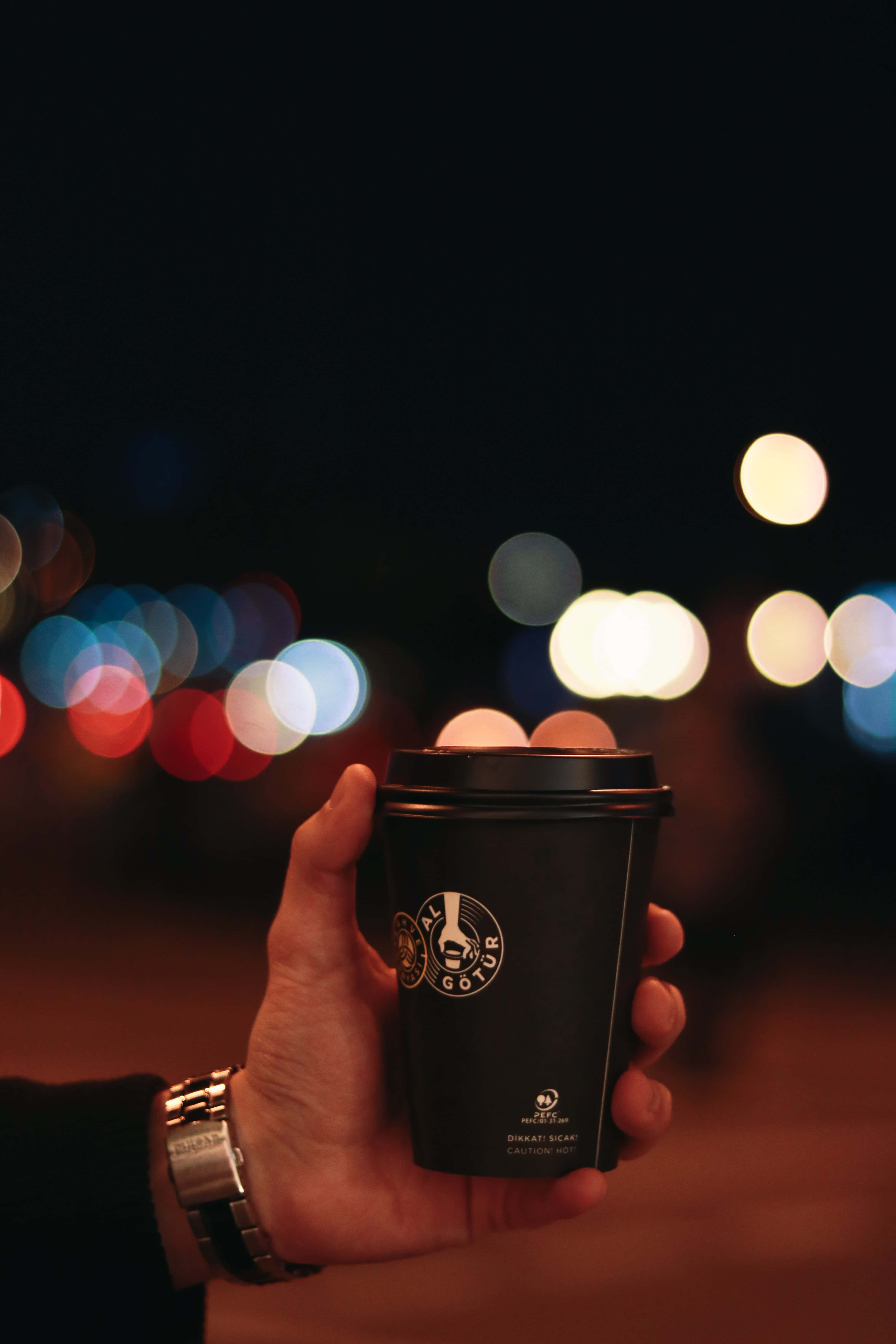 black coffee cup, vibrant bokeh night cityscape, glowing lights, 5K Phone Wallpaper