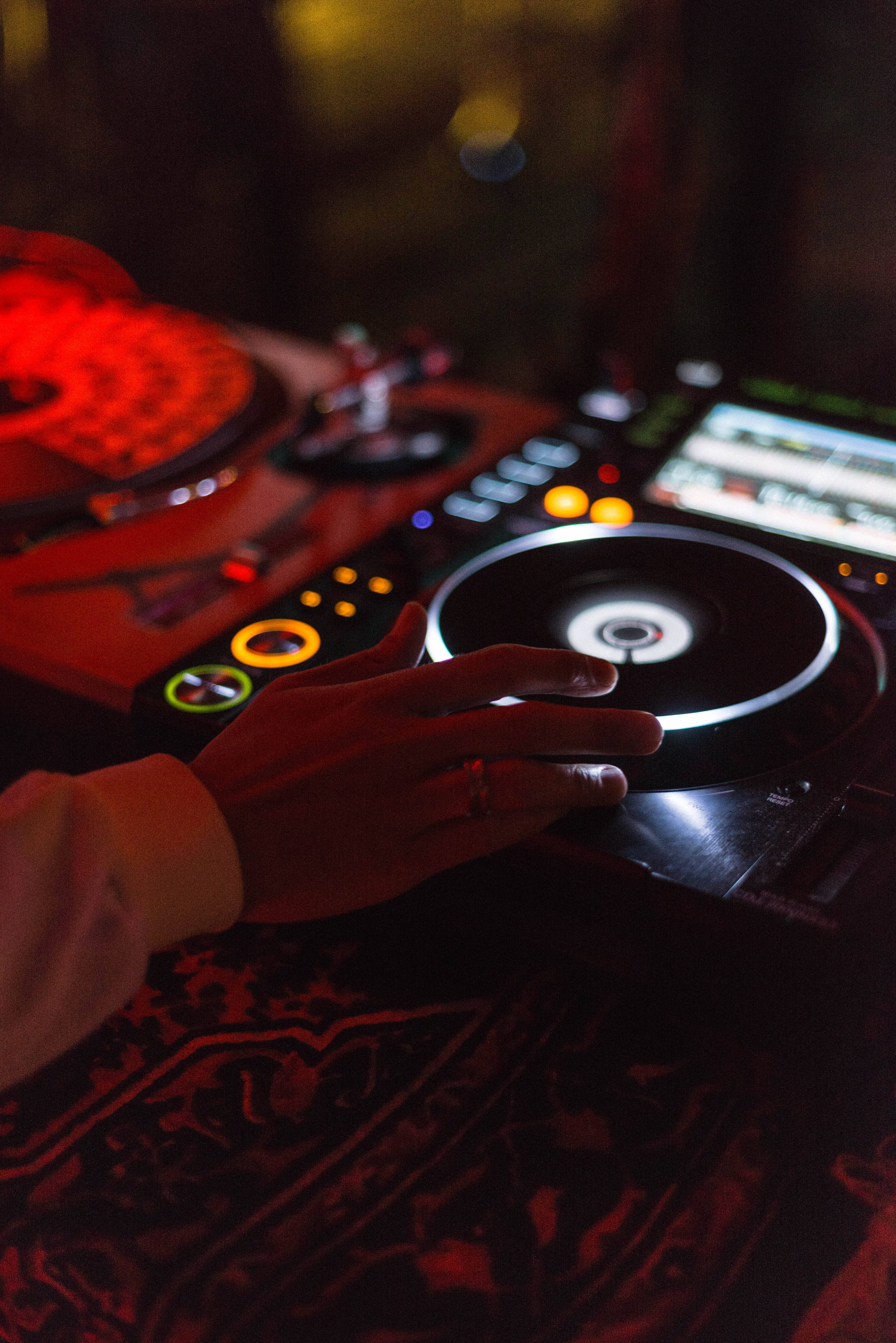 DJ Hand Dark Mixer Equipment, spinning vinyl record, warm red and orange lights, 5K Phone Wallpaper