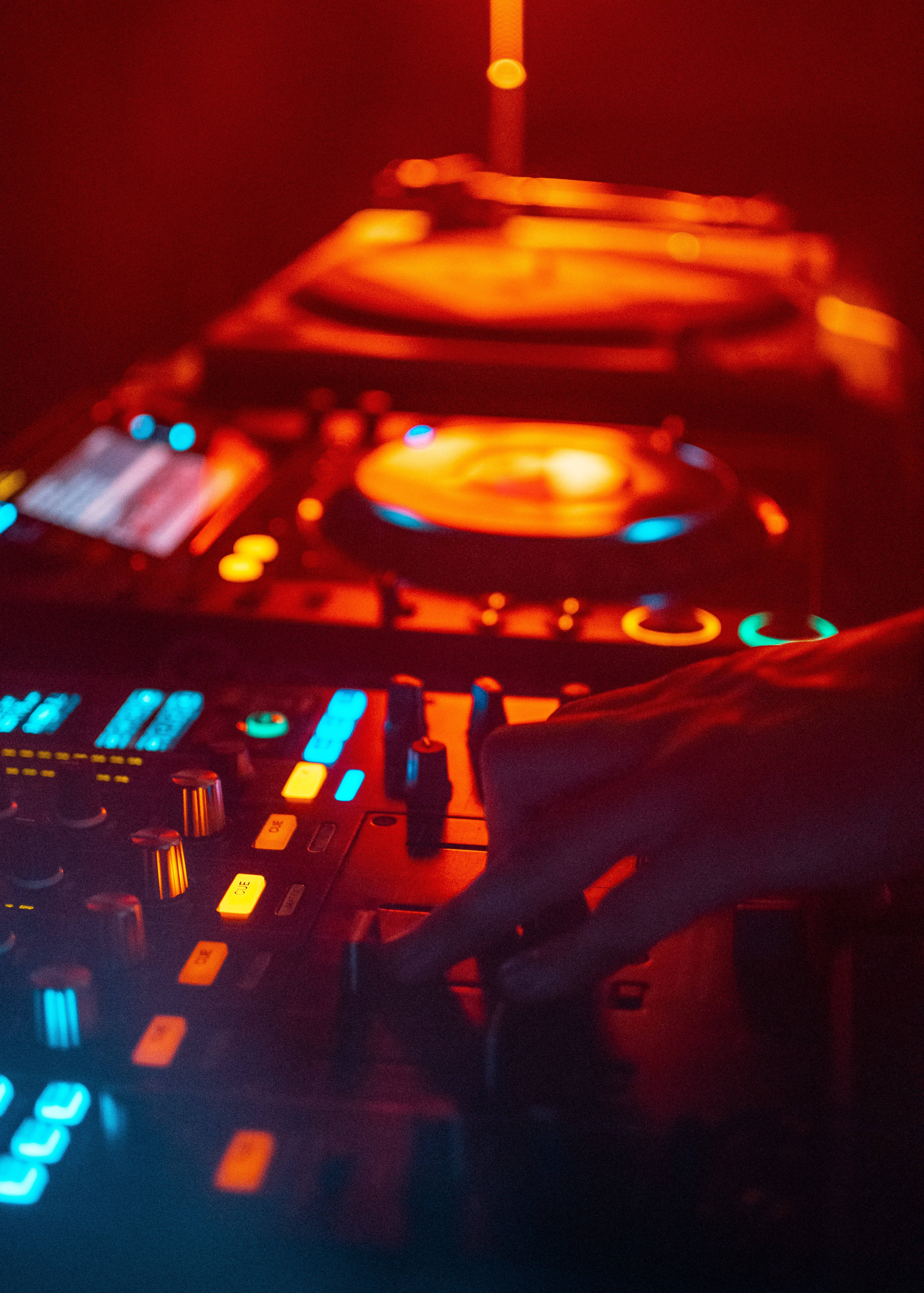 DJ mixer, glowing blue knobs, warm red lights, 4K Phone Wallpaper