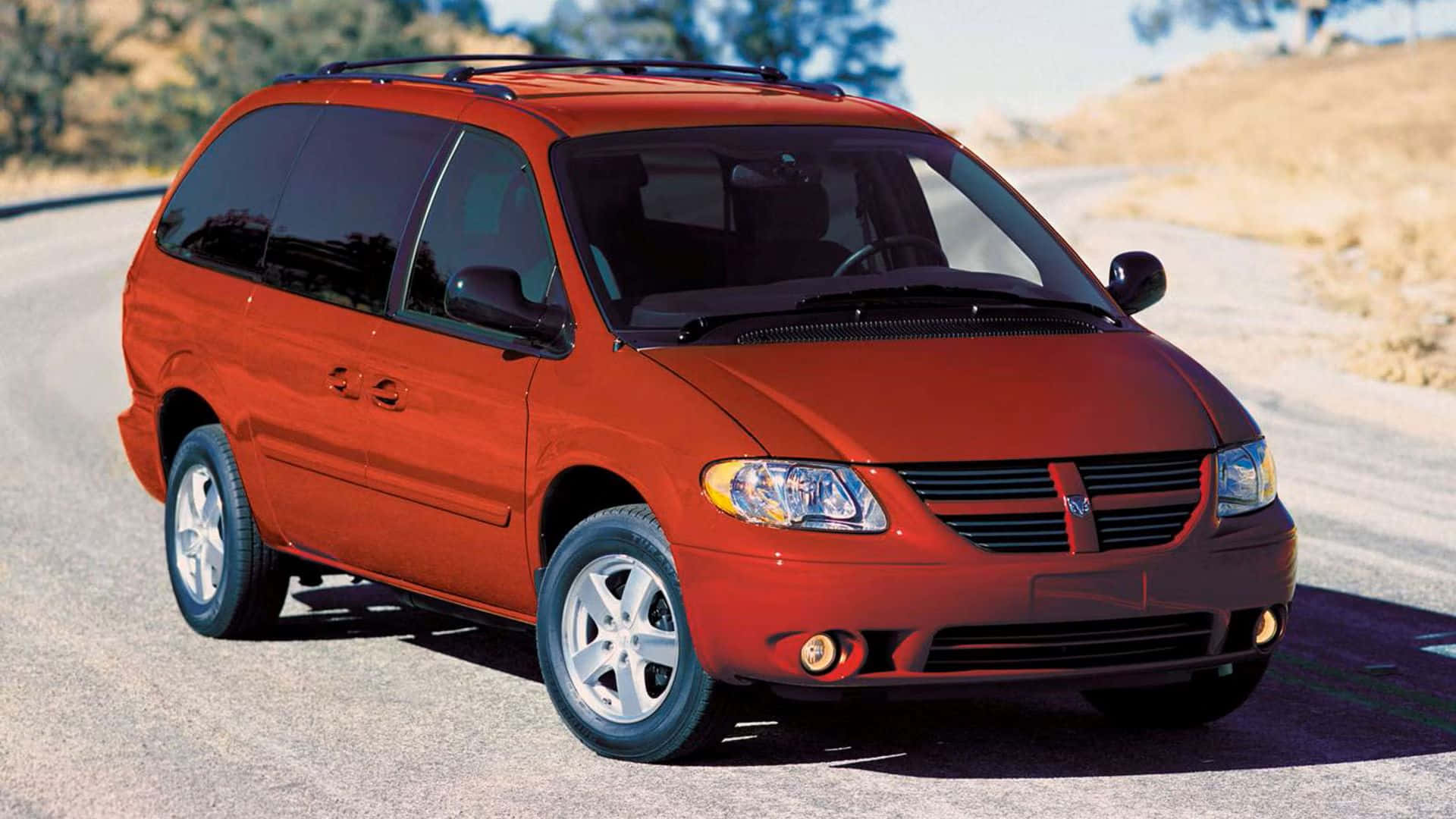 Red Dodge Grand Caravan, sunlit desert road, rocky hills, Full HD Desktop Wallpaper