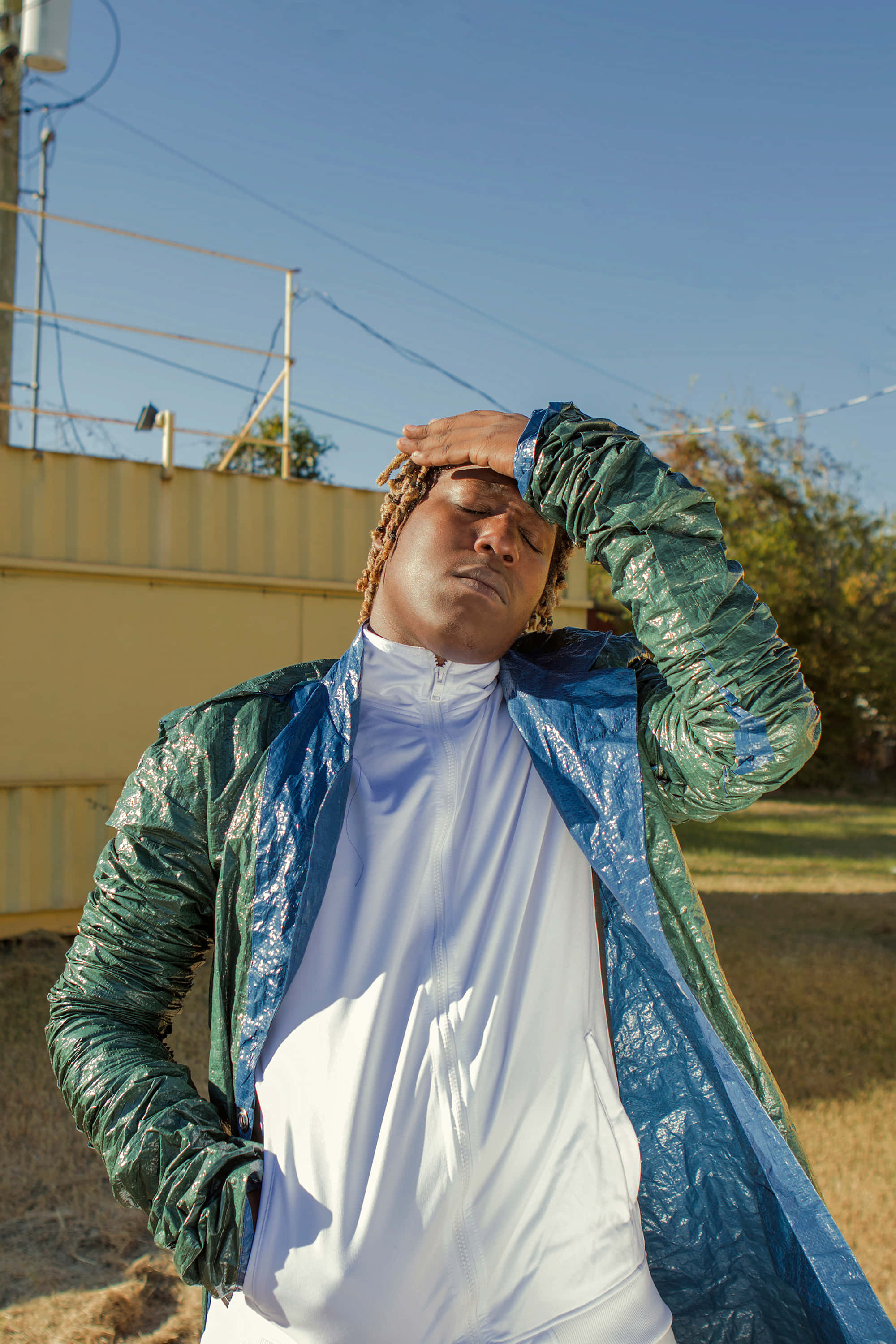 Don Toliver, shiny blue and green plastic jacket, clear blue sky, 2K Phone Wallpaper
