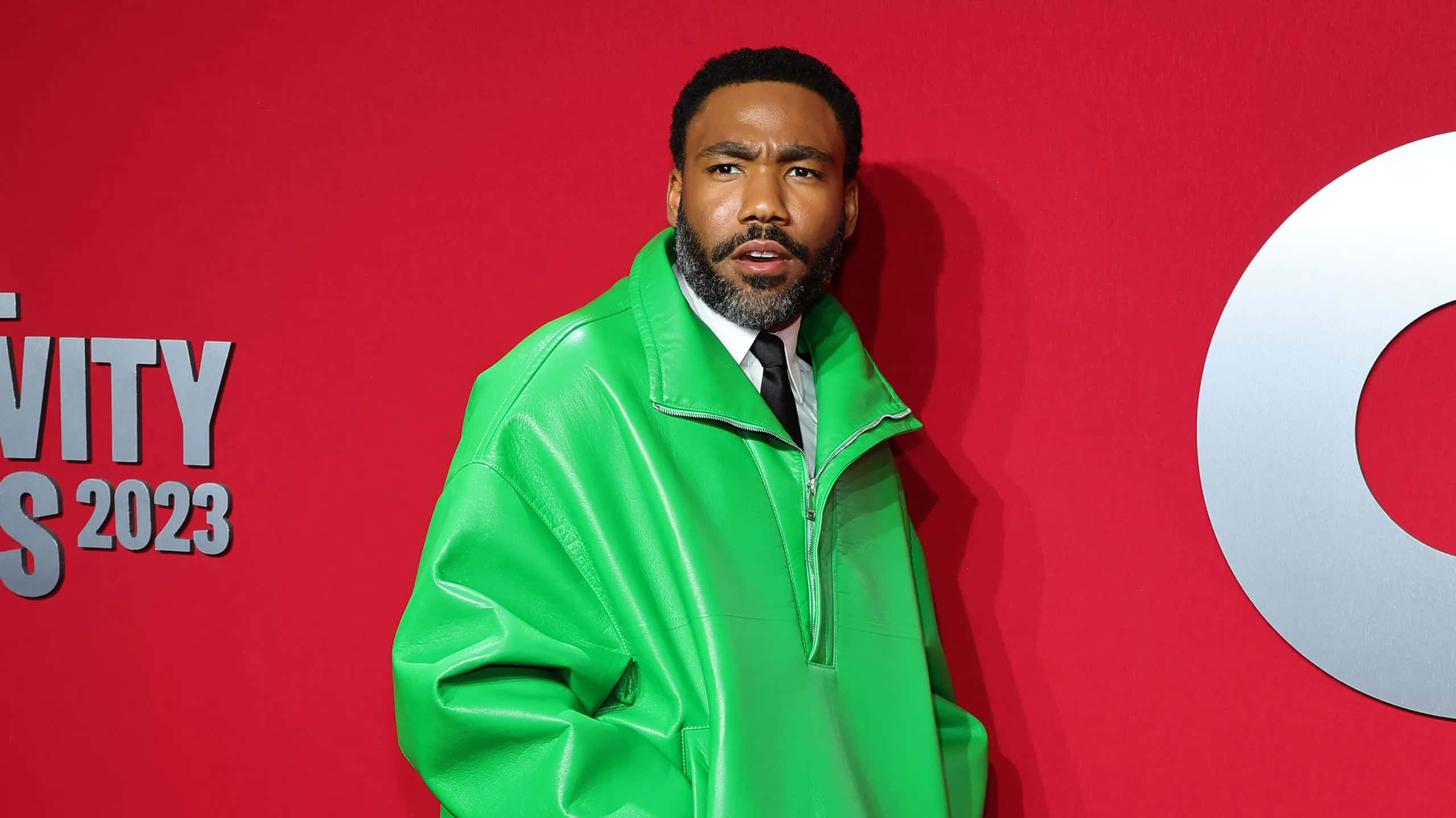 Donald Glover, green jacket, red background, 2K Desktop Wallpaper