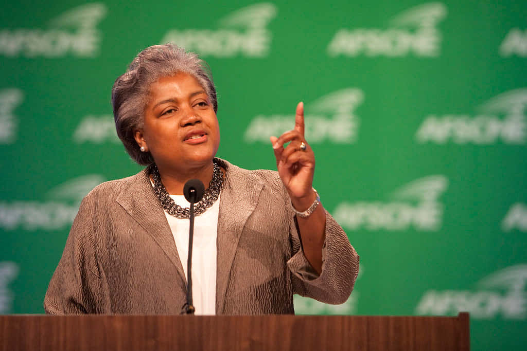 Donna Brazile, green APACHE branded backdrop, podium, SD Desktop Wallpaper