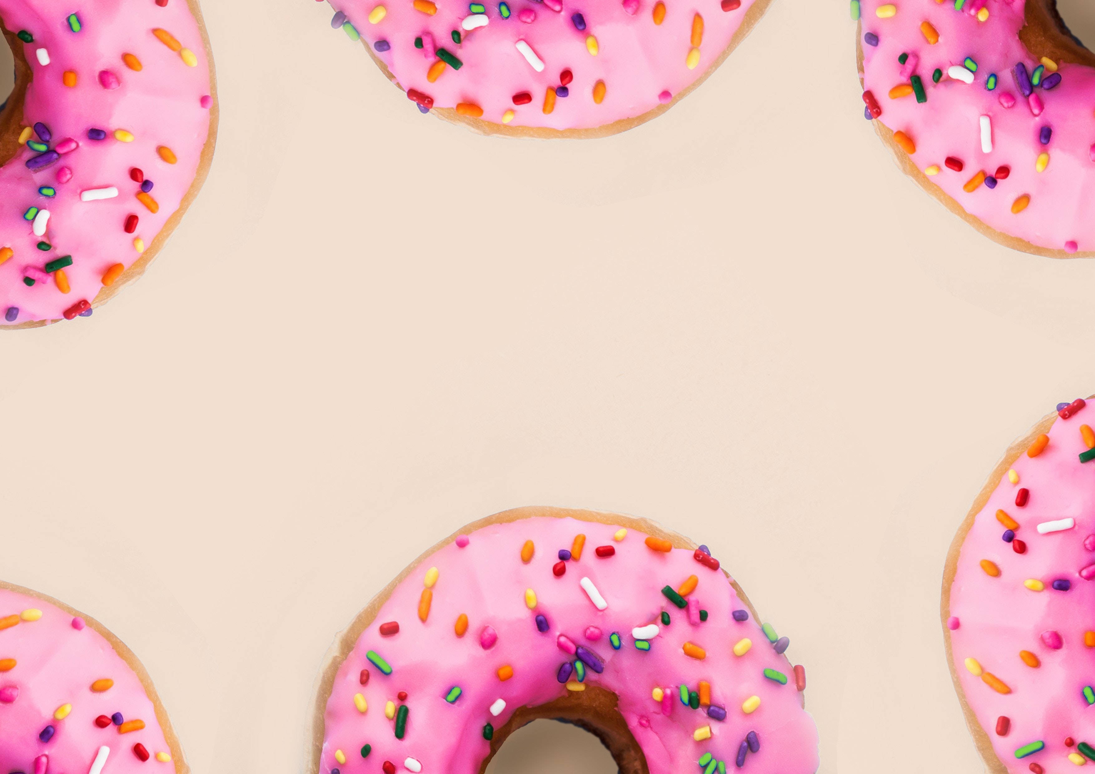 pink frosted donuts, colorful sprinkles, scattered pattern, 2K Desktop Wallpaper