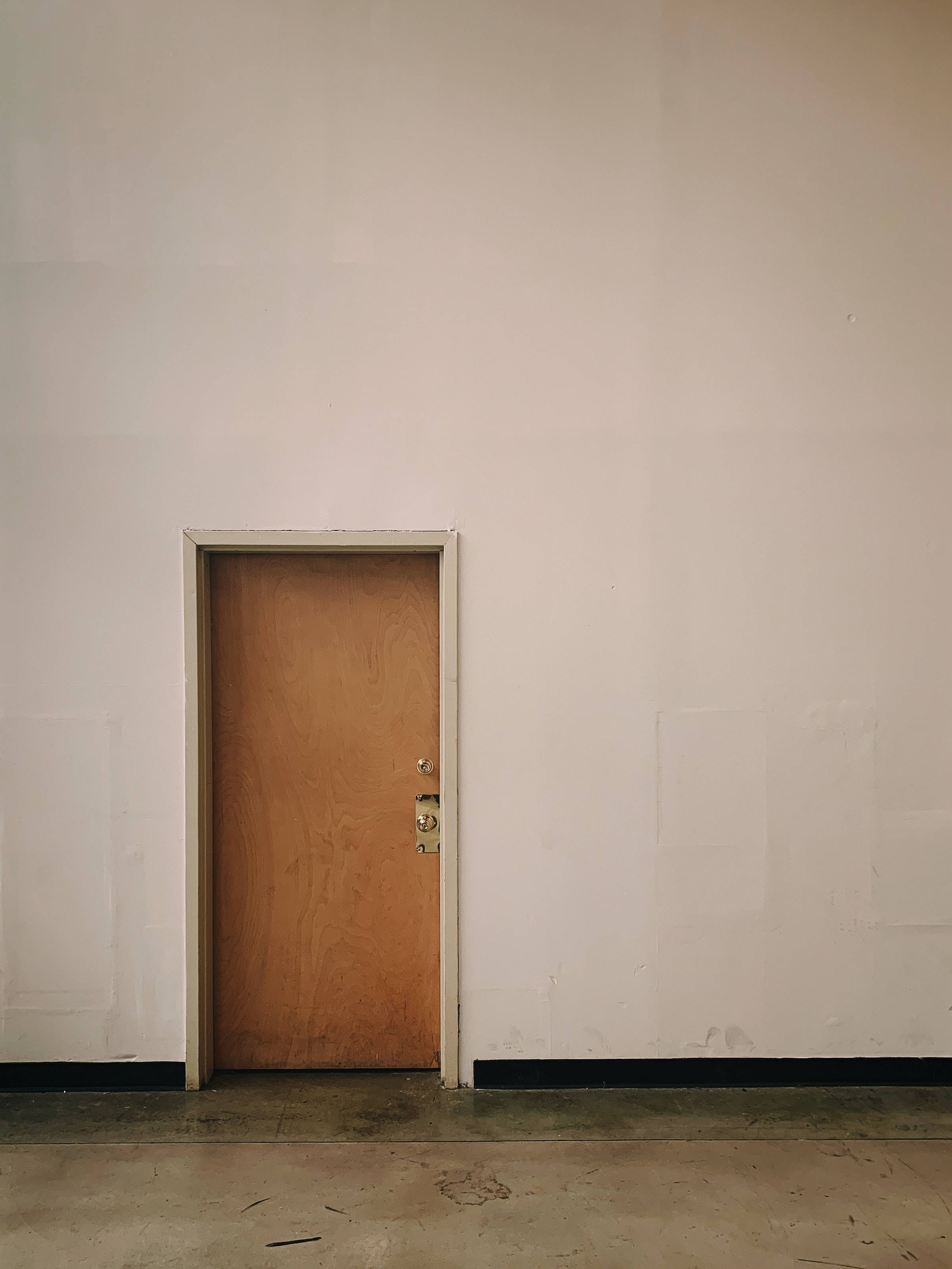 plain brown wooden door, metal handle, stark white wall, 2K Phone Wallpaper