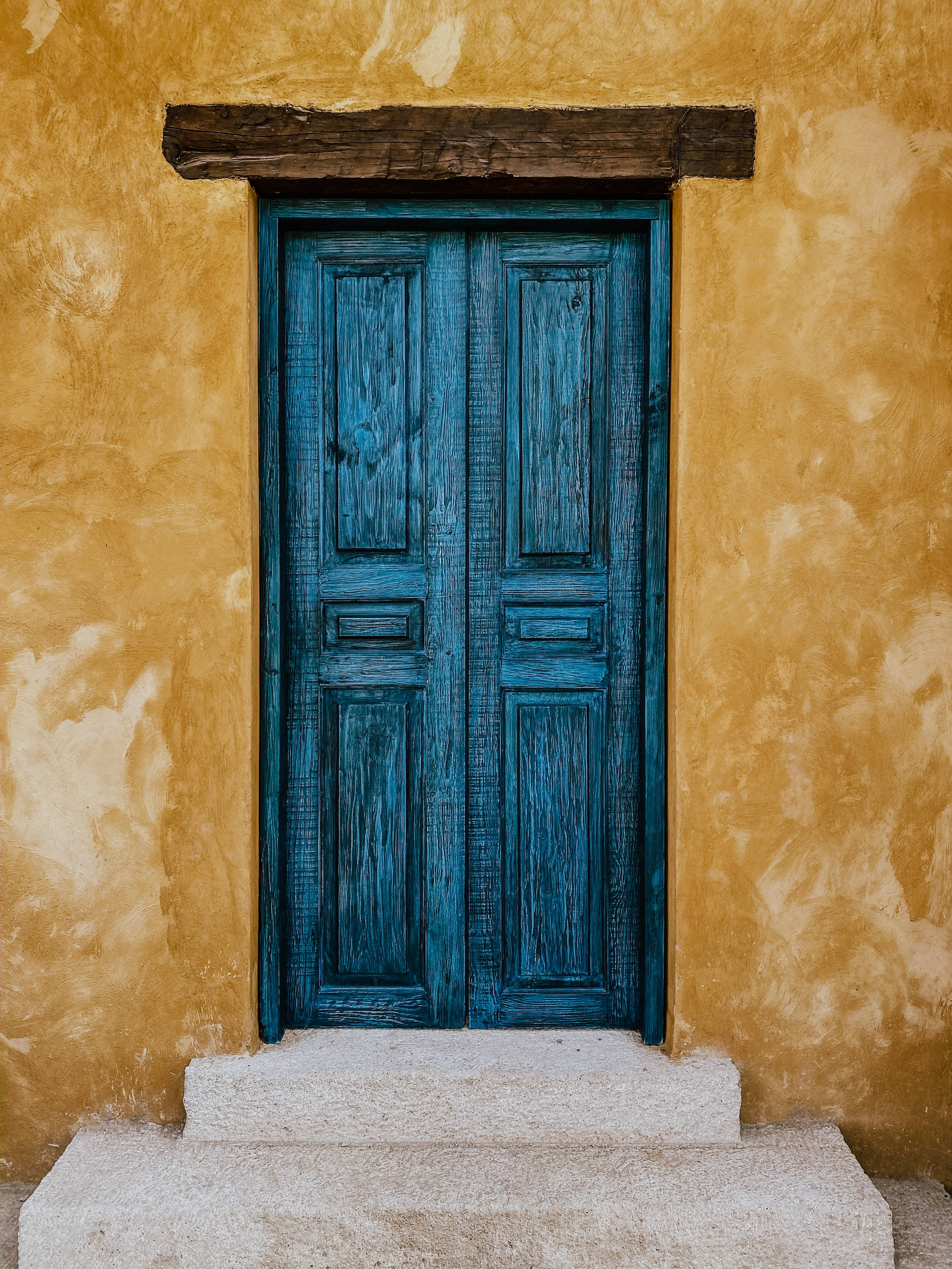 antique wooden blue double door, textured ochre wall, stone steps, 2K Phone Wallpaper