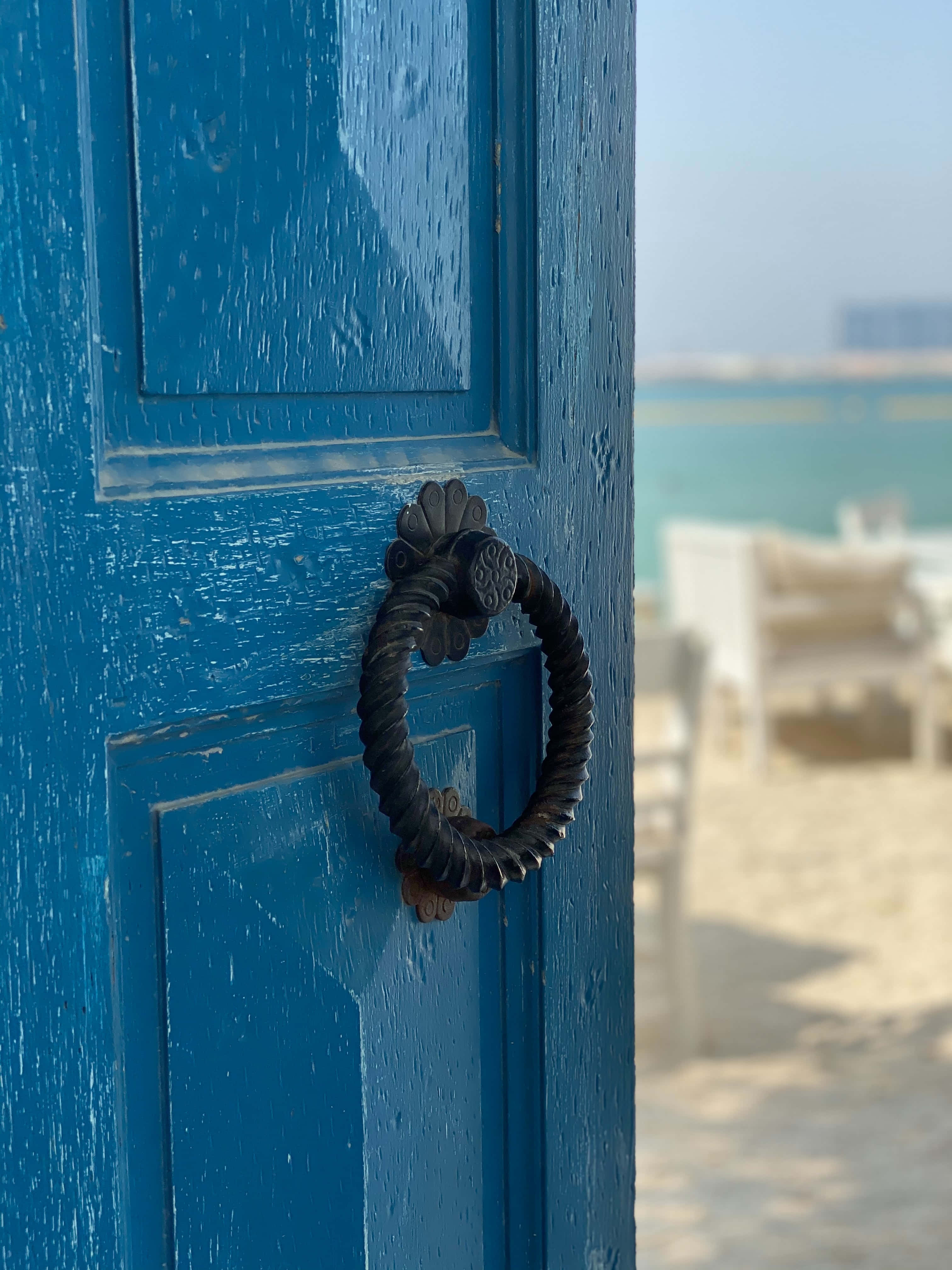 blue wooden door, twisted black metal knocker, turquoise water, 4K Phone Wallpaper