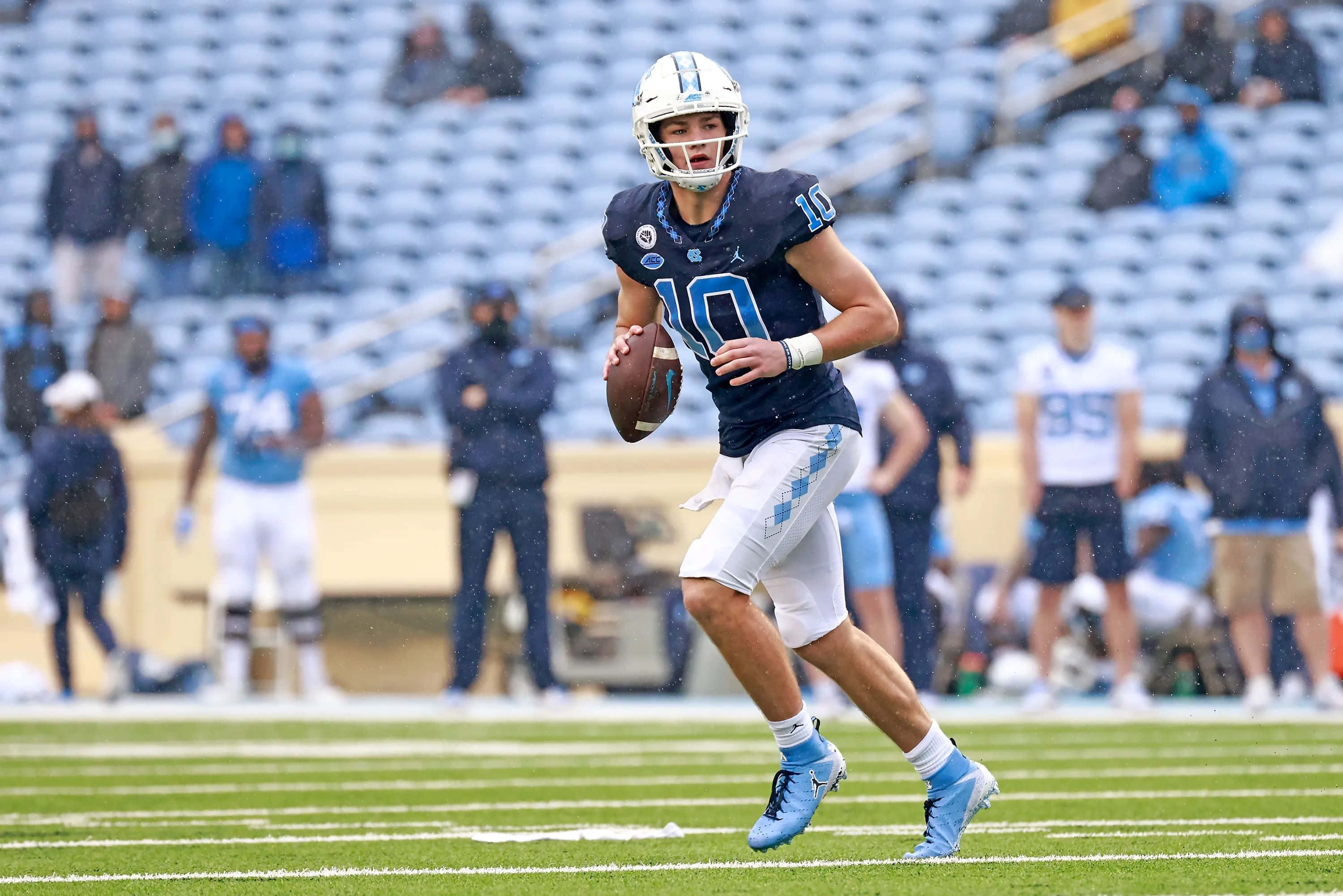 Drake Maye, blue uniform, rainy field, 2K Desktop Wallpaper