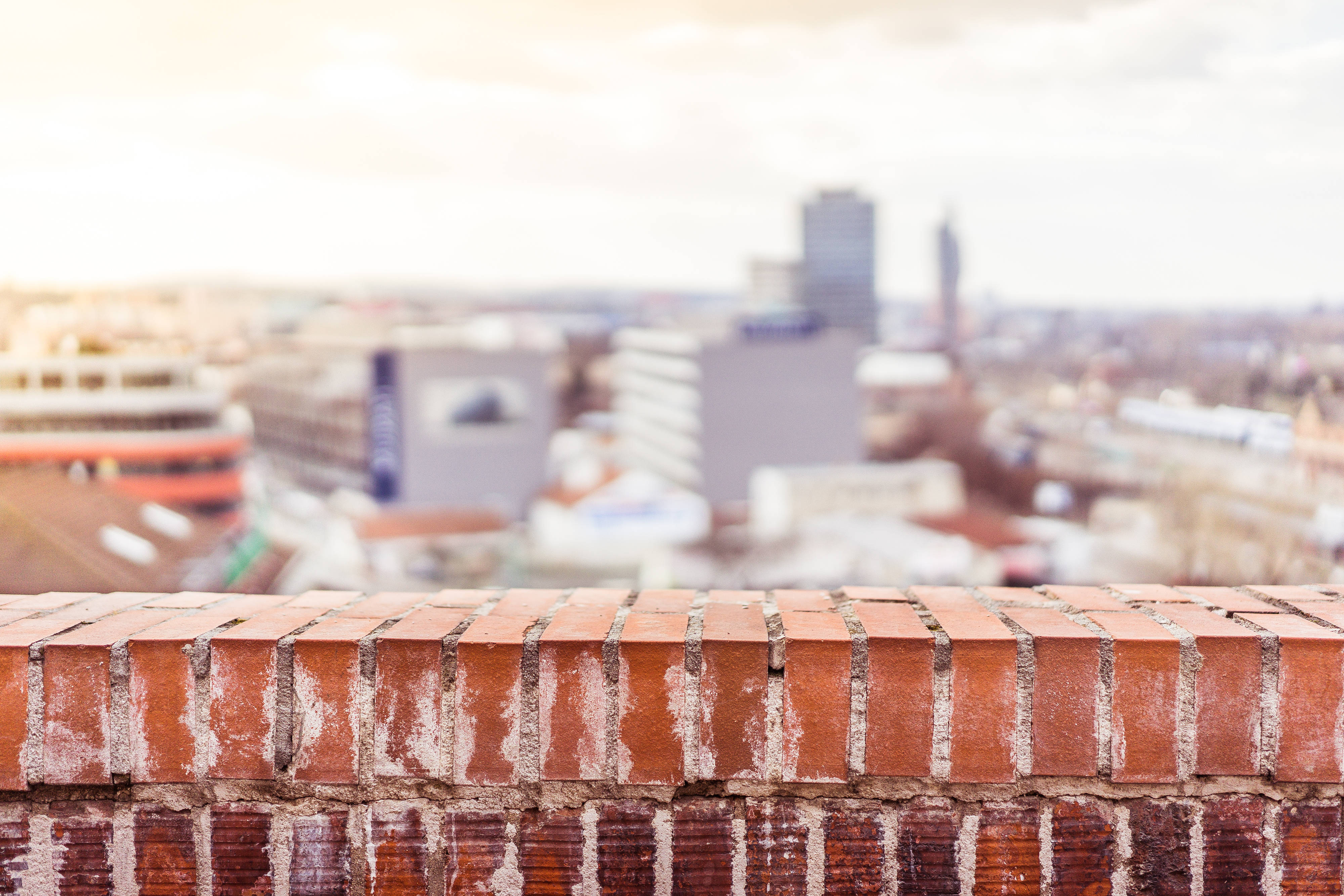 weathered brick ledge, softly blurred cityscape, hazy sky, 4K Desktop Wallpaper