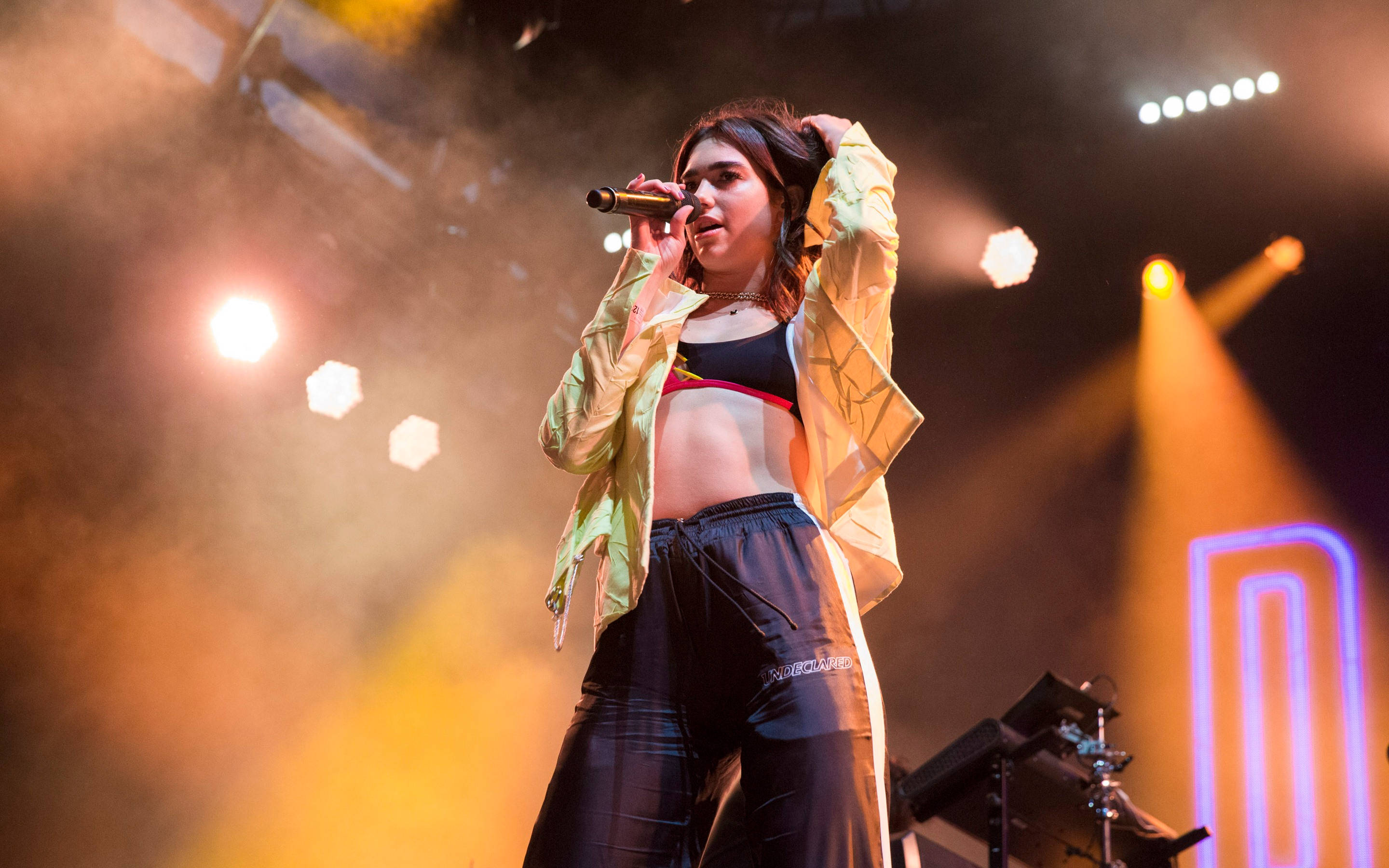 Dua Lipa, performing on stage, warm spotlights, 2K Desktop Wallpaper