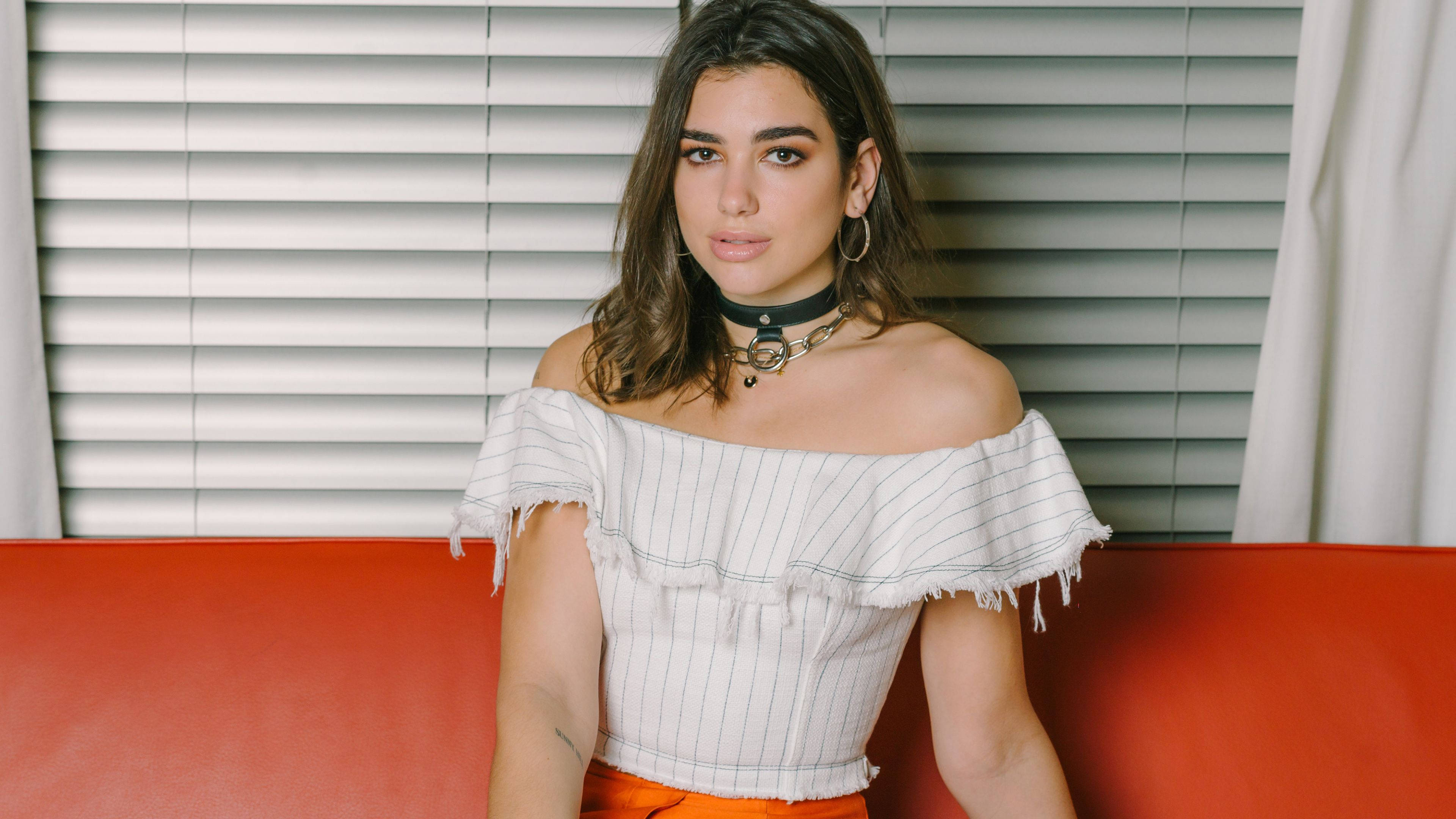 Dua Lipa, white blinds, vibrant red couch, 4K Desktop Wallpaper