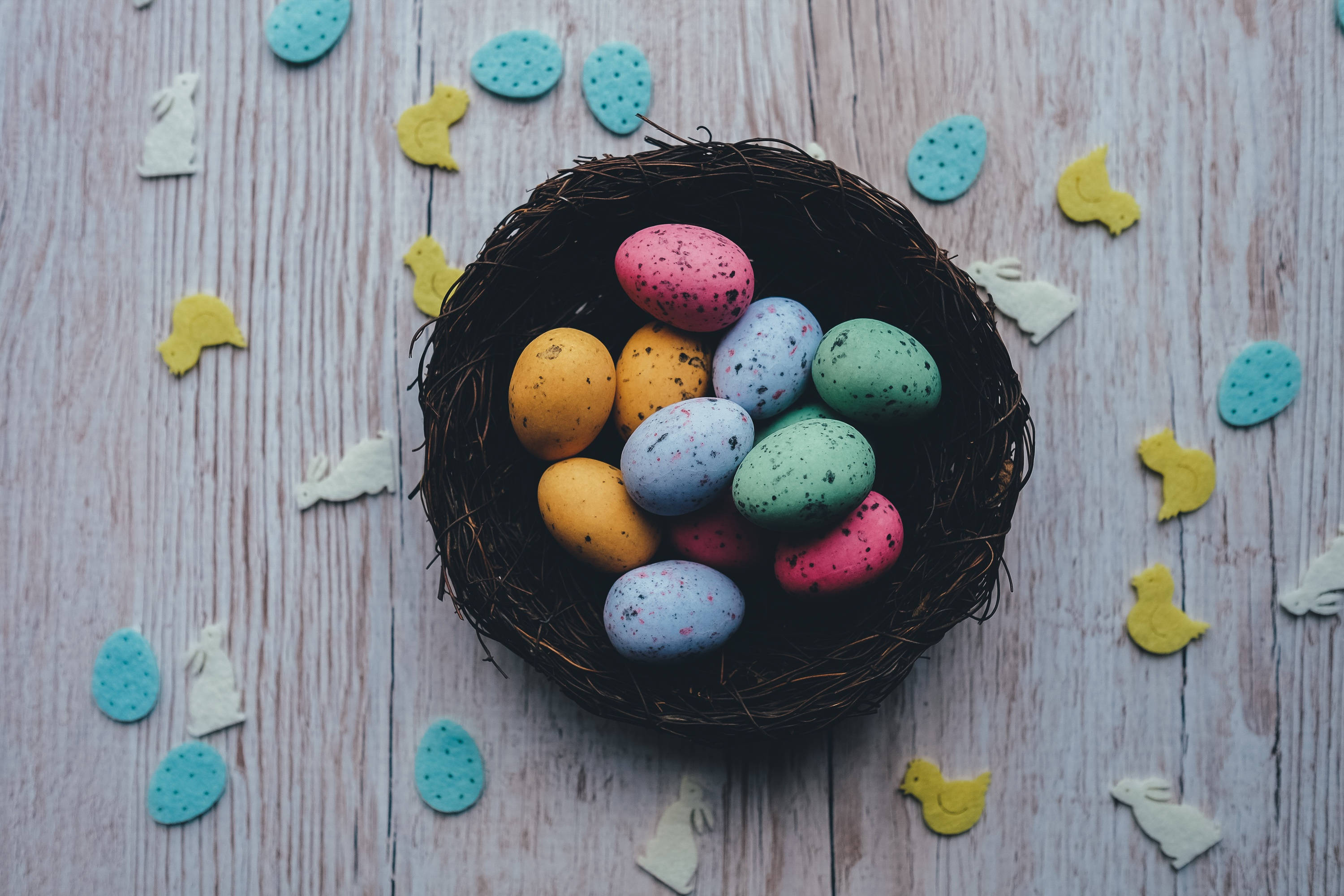 colorful speckled Easter eggs, woven nest, rustic wooden surface, 2K Desktop Wallpaper