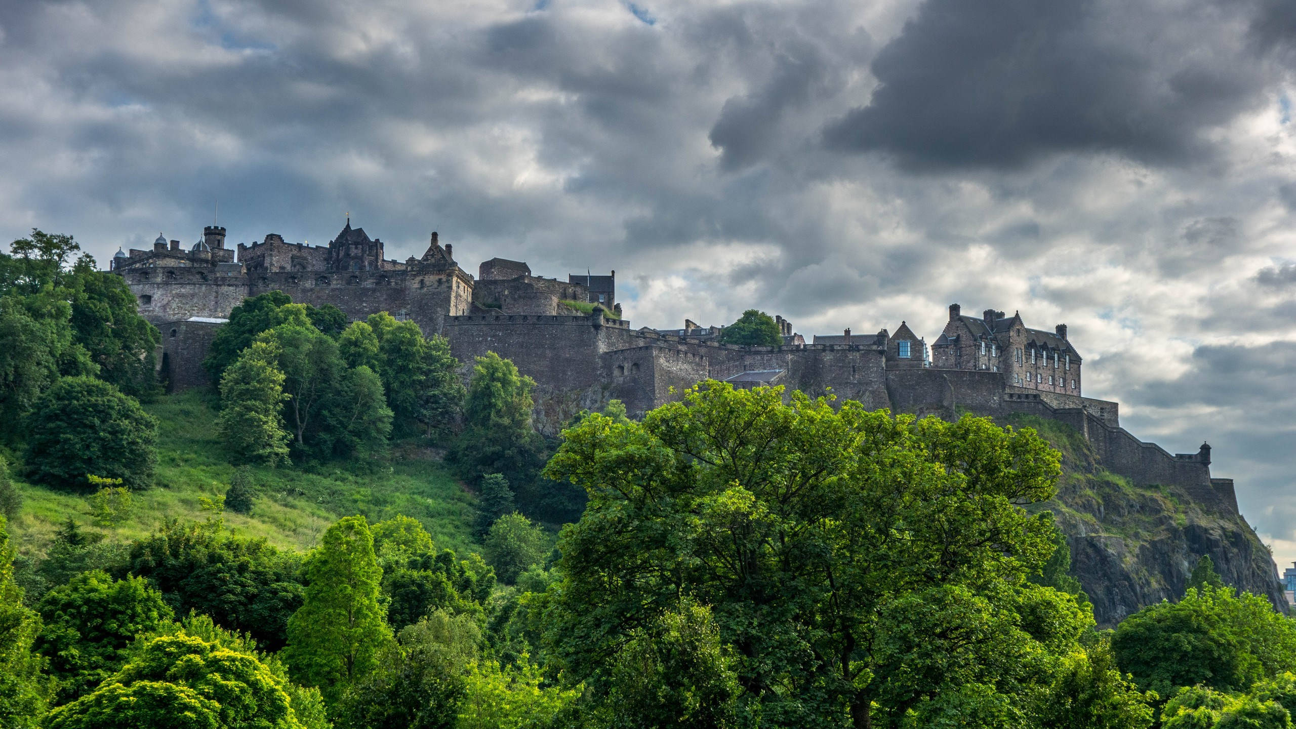 Edinburgh Castle, grassy hill, dramatic cloudy skies, 2K Desktop Wallpaper