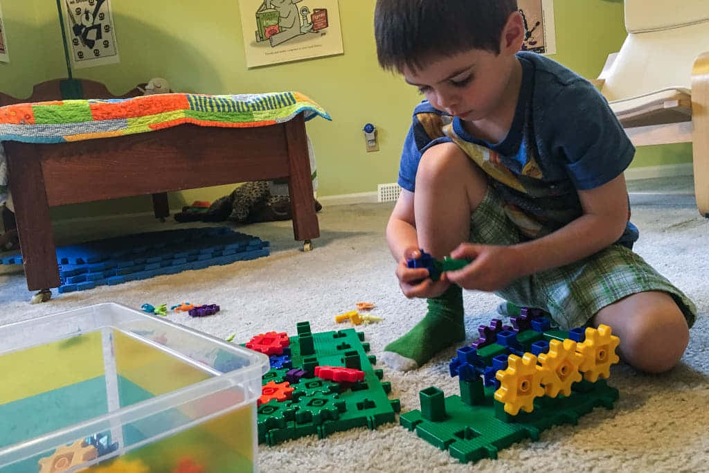 young boy, colorful plastic gears and blocks, carpeted floor, SD Desktop Wallpaper