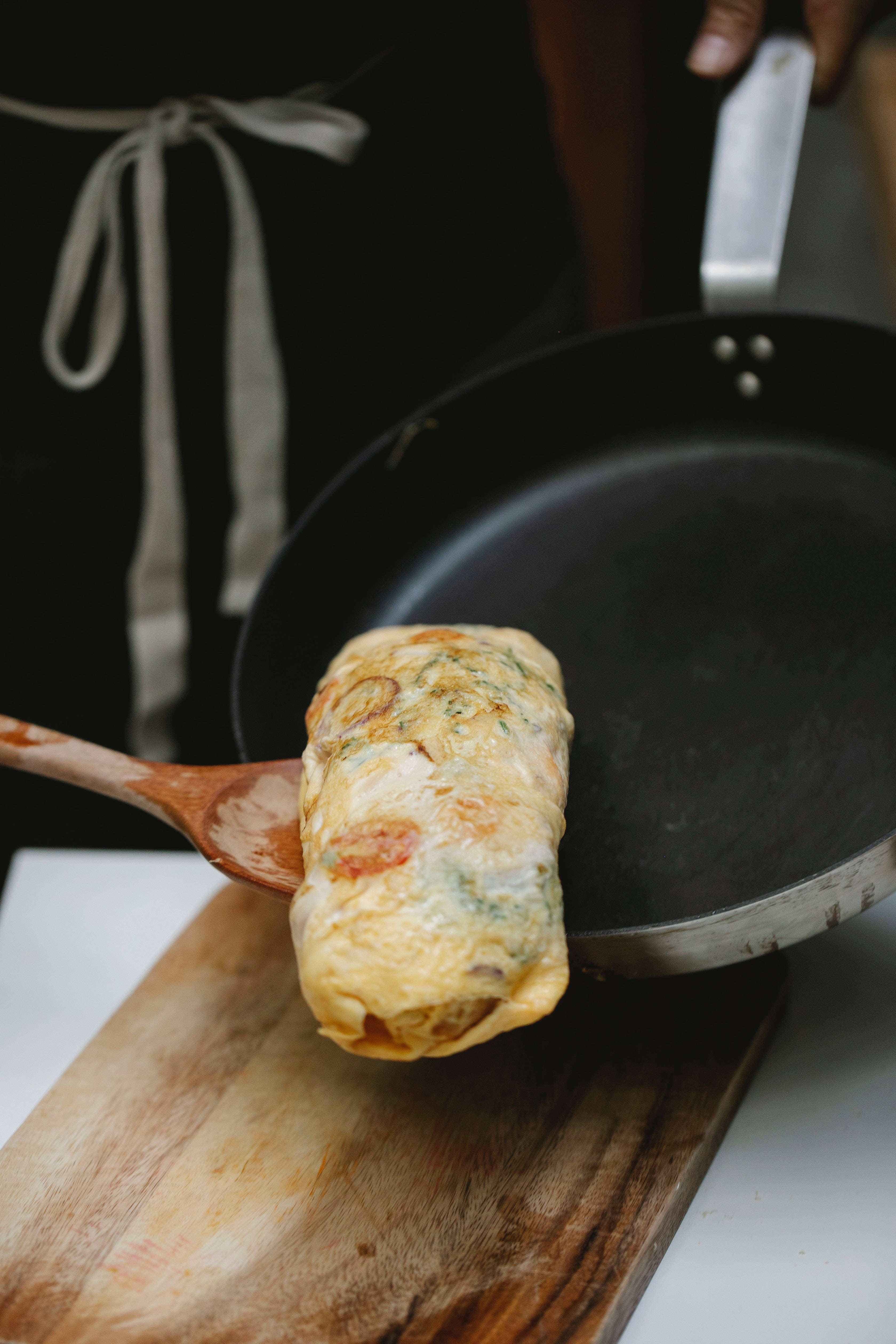 egg roll, black frying pan, wooden spatula, 4K Phone Wallpaper