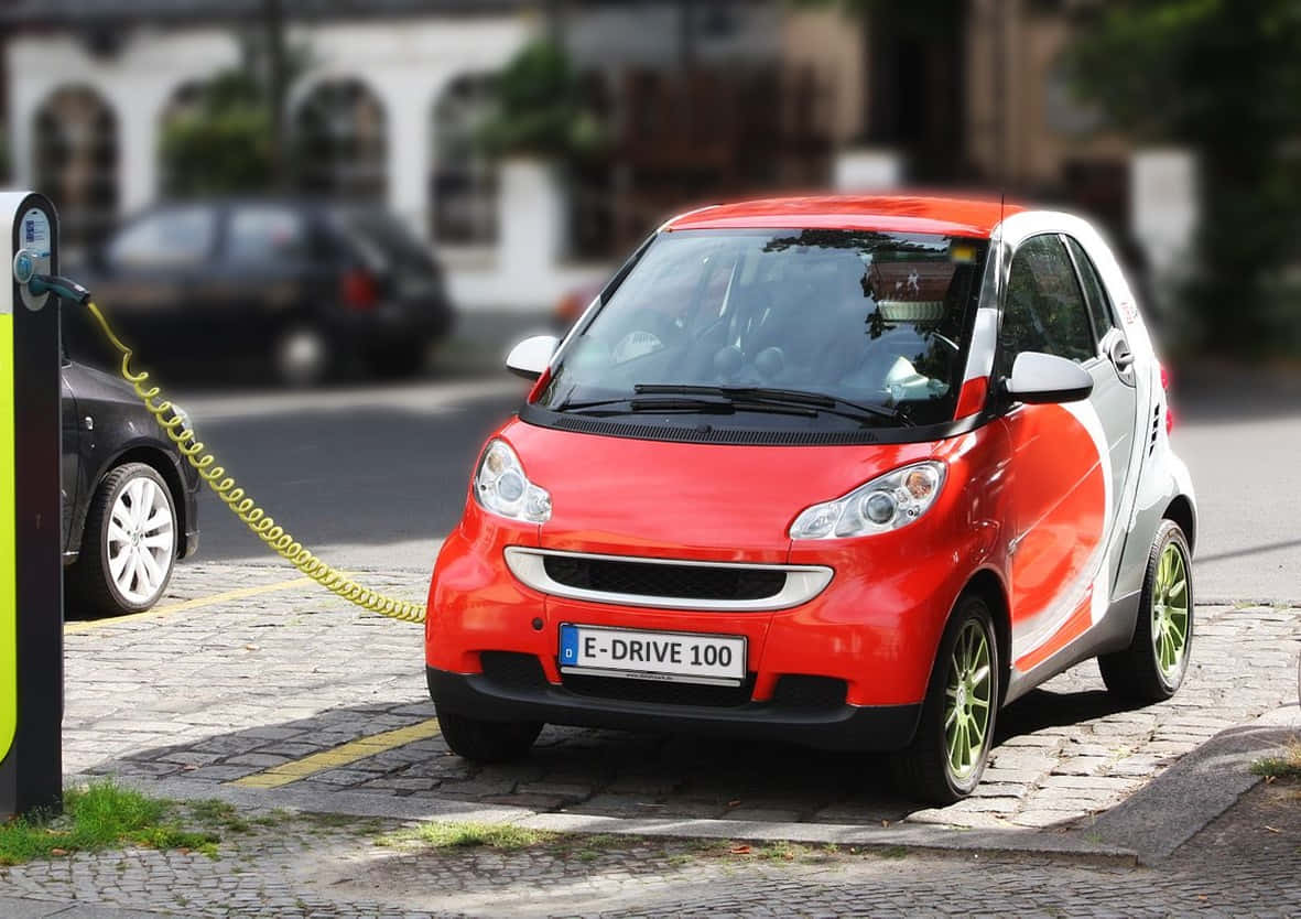 vibrant red smart car, green wheels, charging station, SD Desktop Wallpaper