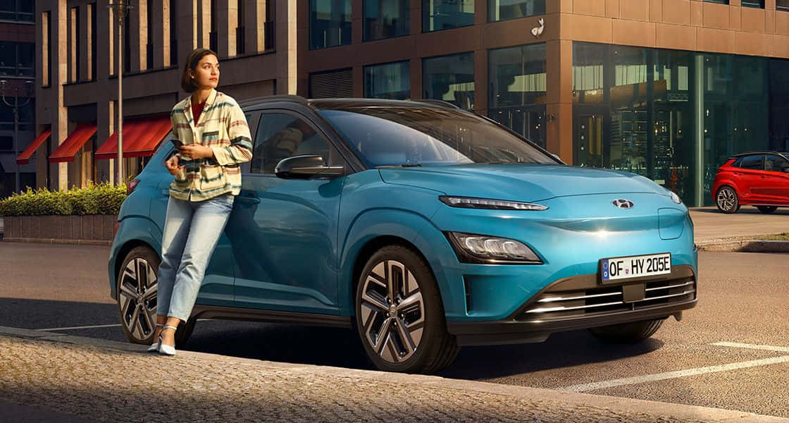 vibrant blue electric car, sunlit city street, modern buildings, SD Desktop Wallpaper