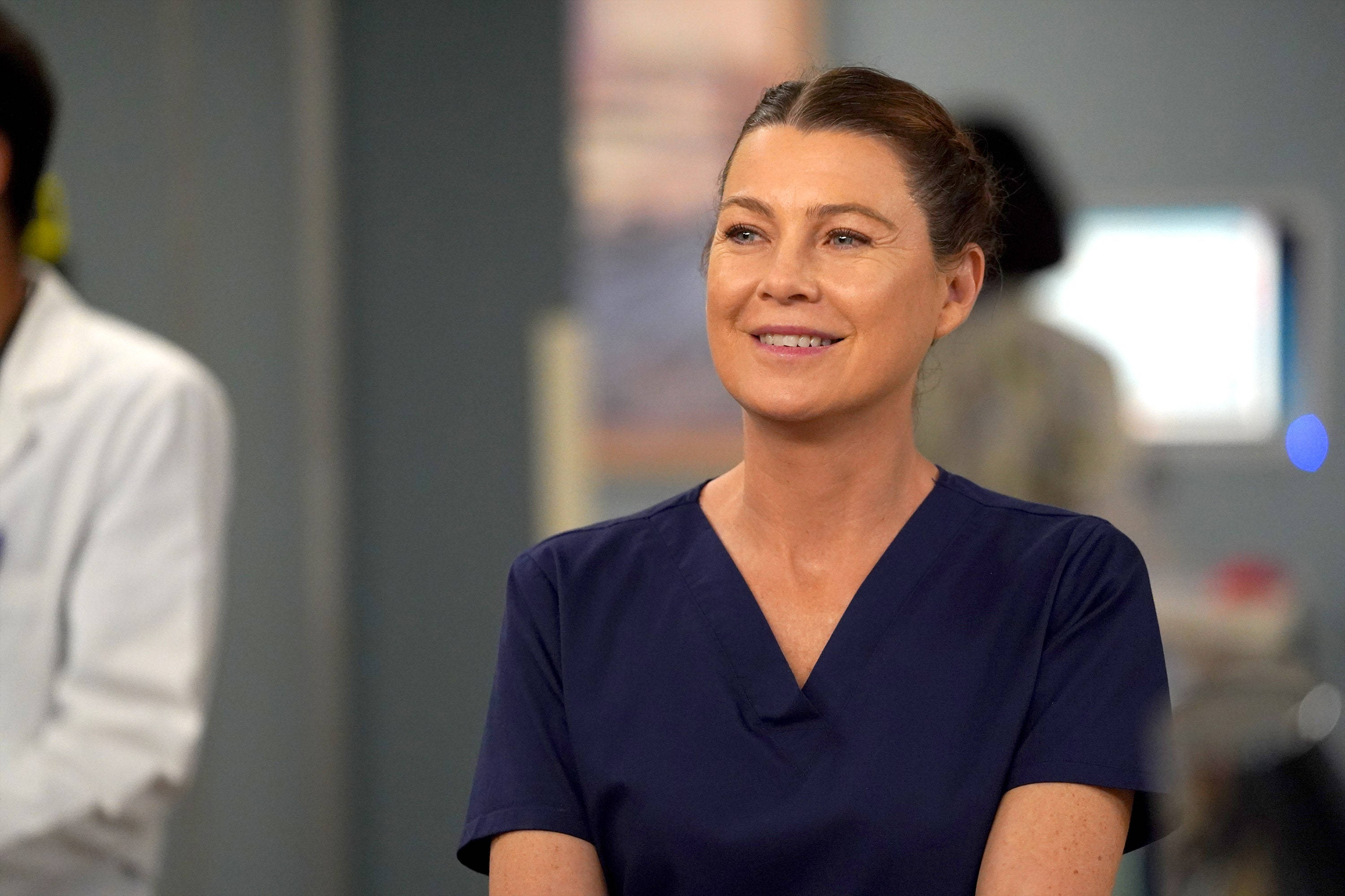 Ellen Pompeo, navy scrubs, softly lit medical facility, 2K Desktop Wallpaper