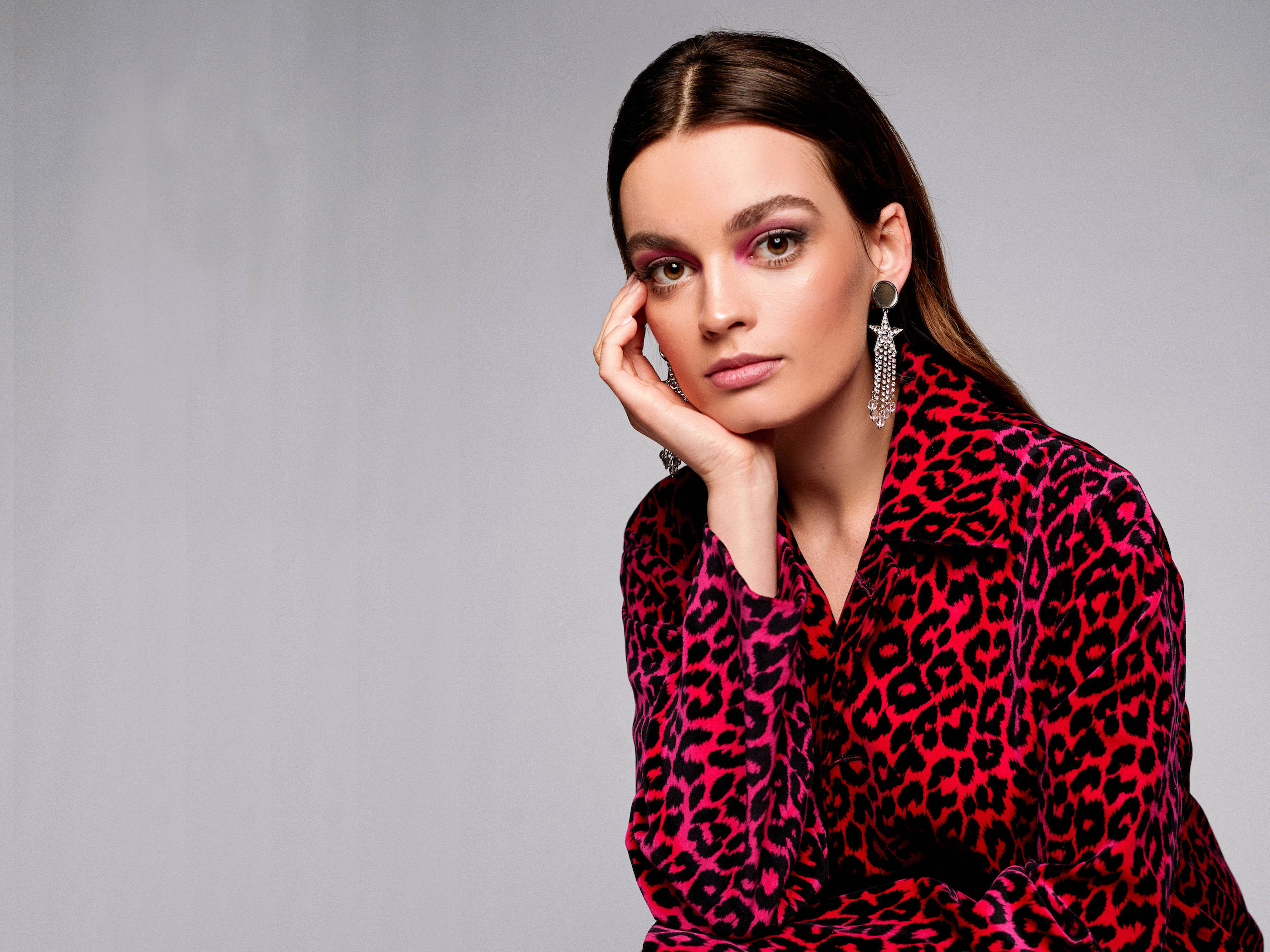 Emma Mackey, vibrant red leopard print blouse, neutral gray background, 2K Desktop Wallpaper