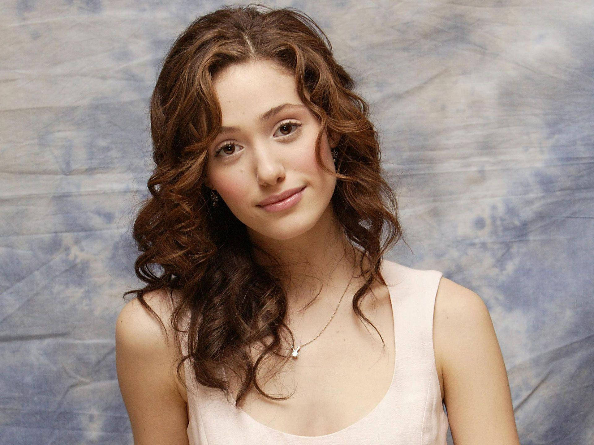 Emmy Rossum, wavy brown hair, textured blue-gray backdrop, Full HD Desktop Wallpaper
