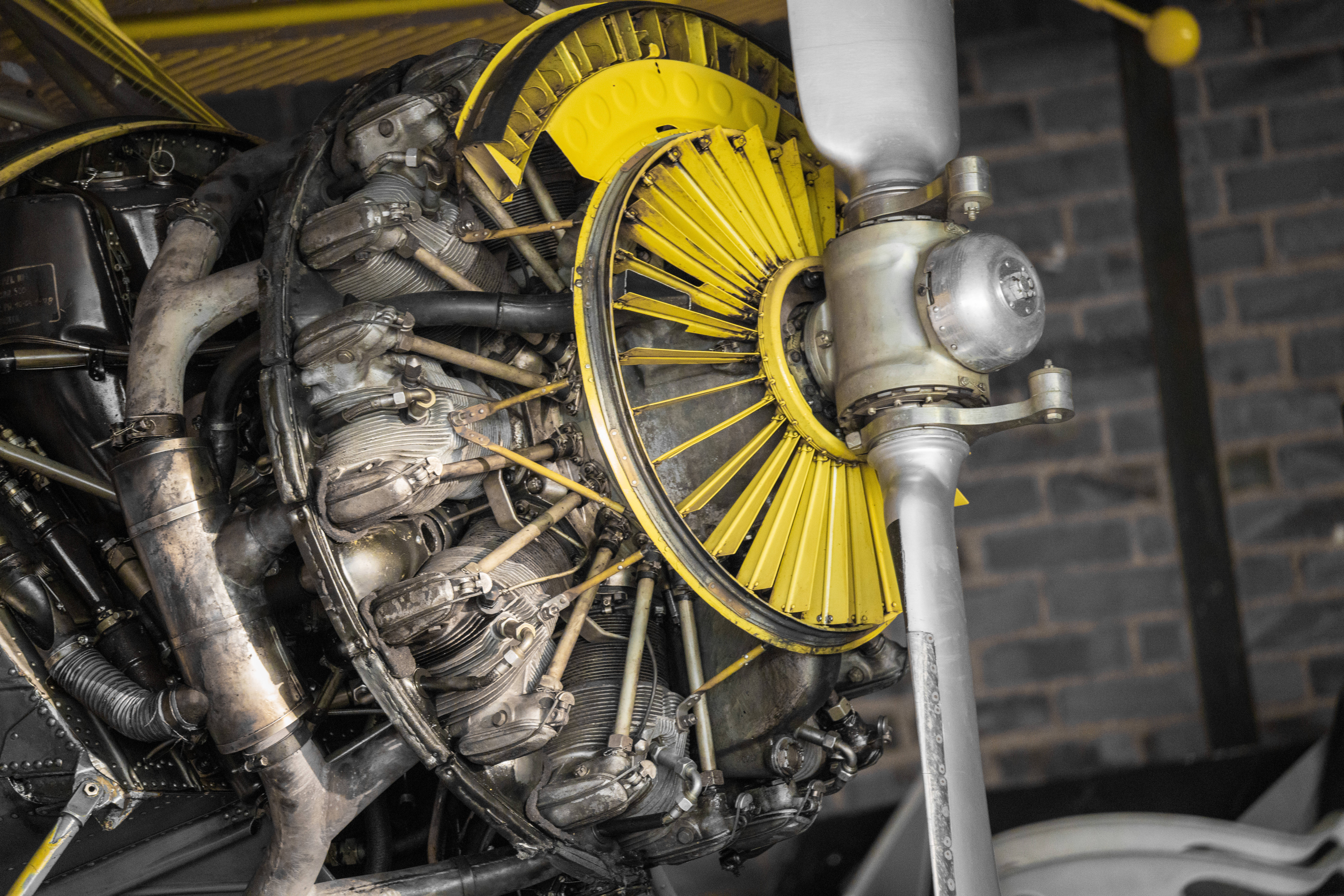 radial aircraft engine, bright yellow spinner, dark brick wall, 8K Desktop Wallpaper