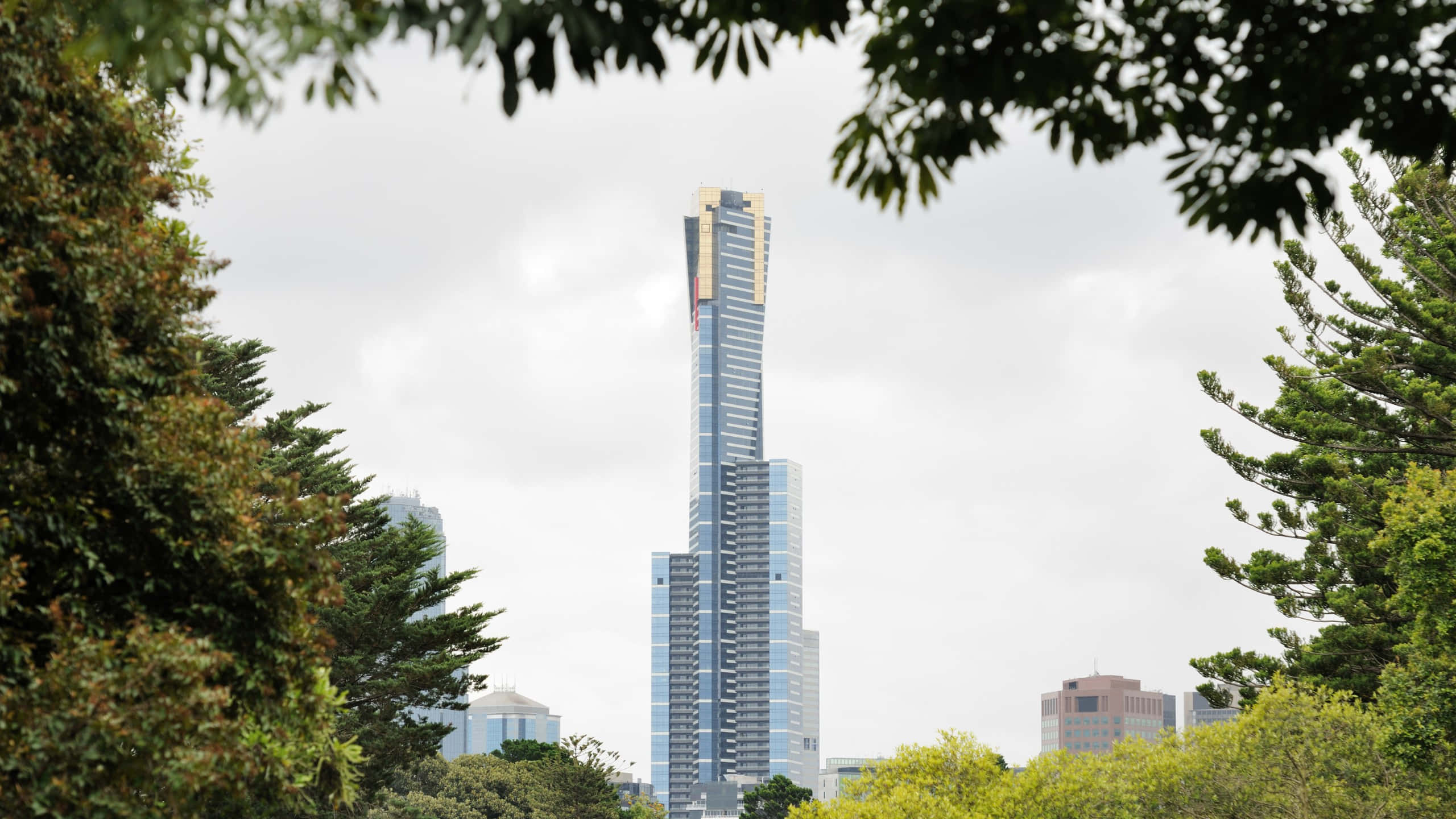 Eureka Tower, lush green trees, overcast sky, 2K Desktop Wallpaper