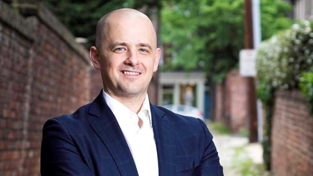 Evan McMullin, navy suit, brick wall, SD Desktop Wallpaper
