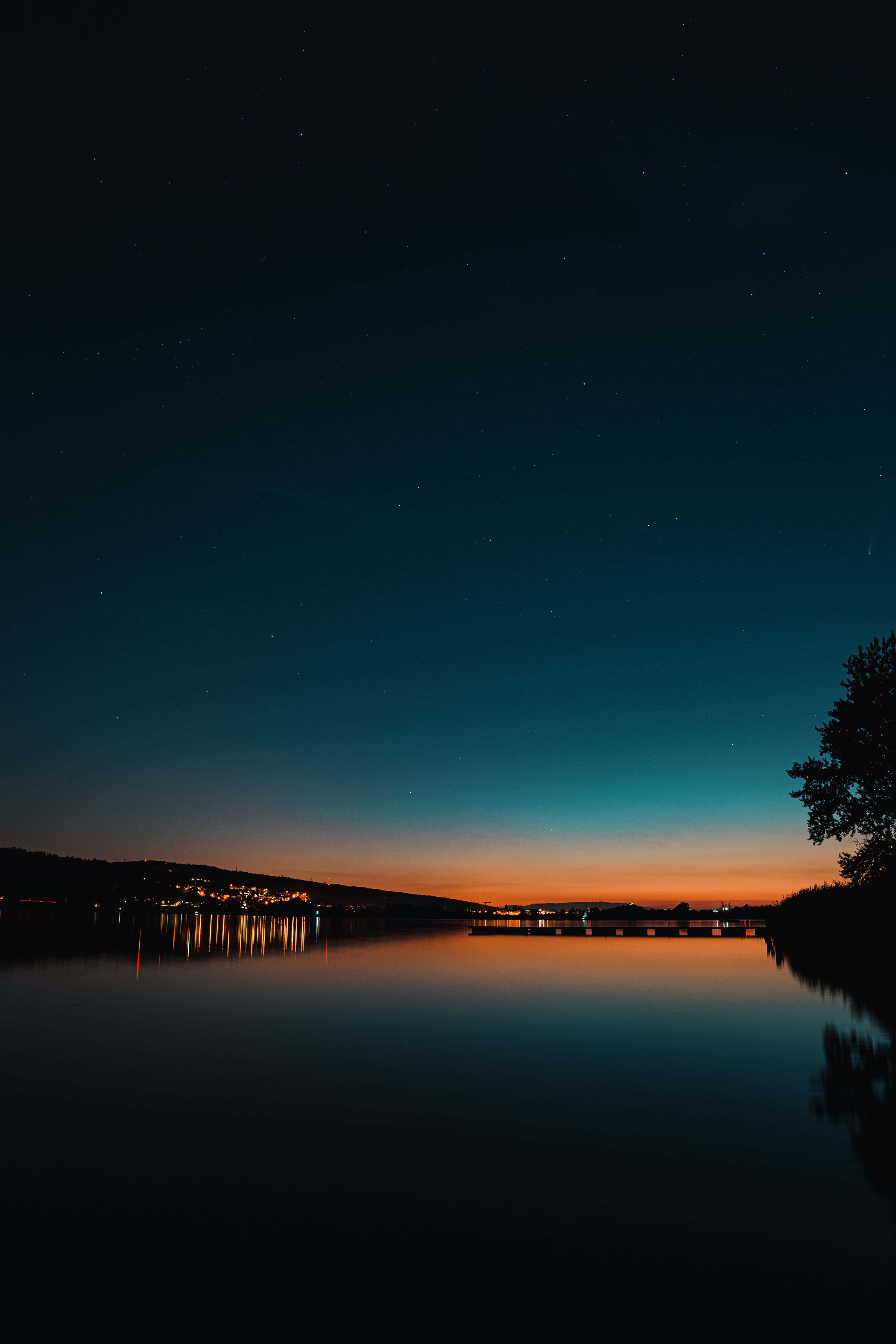 starry evening sky, deep blue to orange gradient, lit buildings, 5K Phone Wallpaper