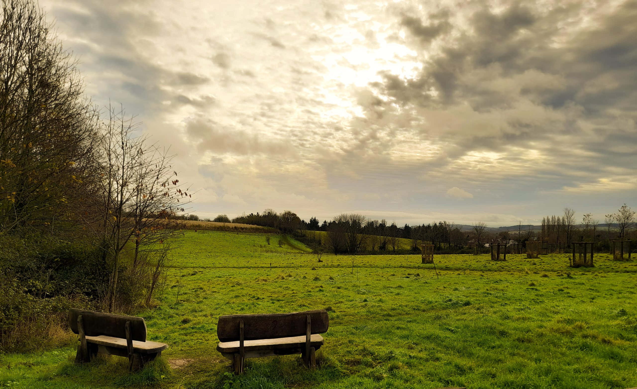 Exeter, wooden benches, vast green field, 2K Desktop Wallpaper
