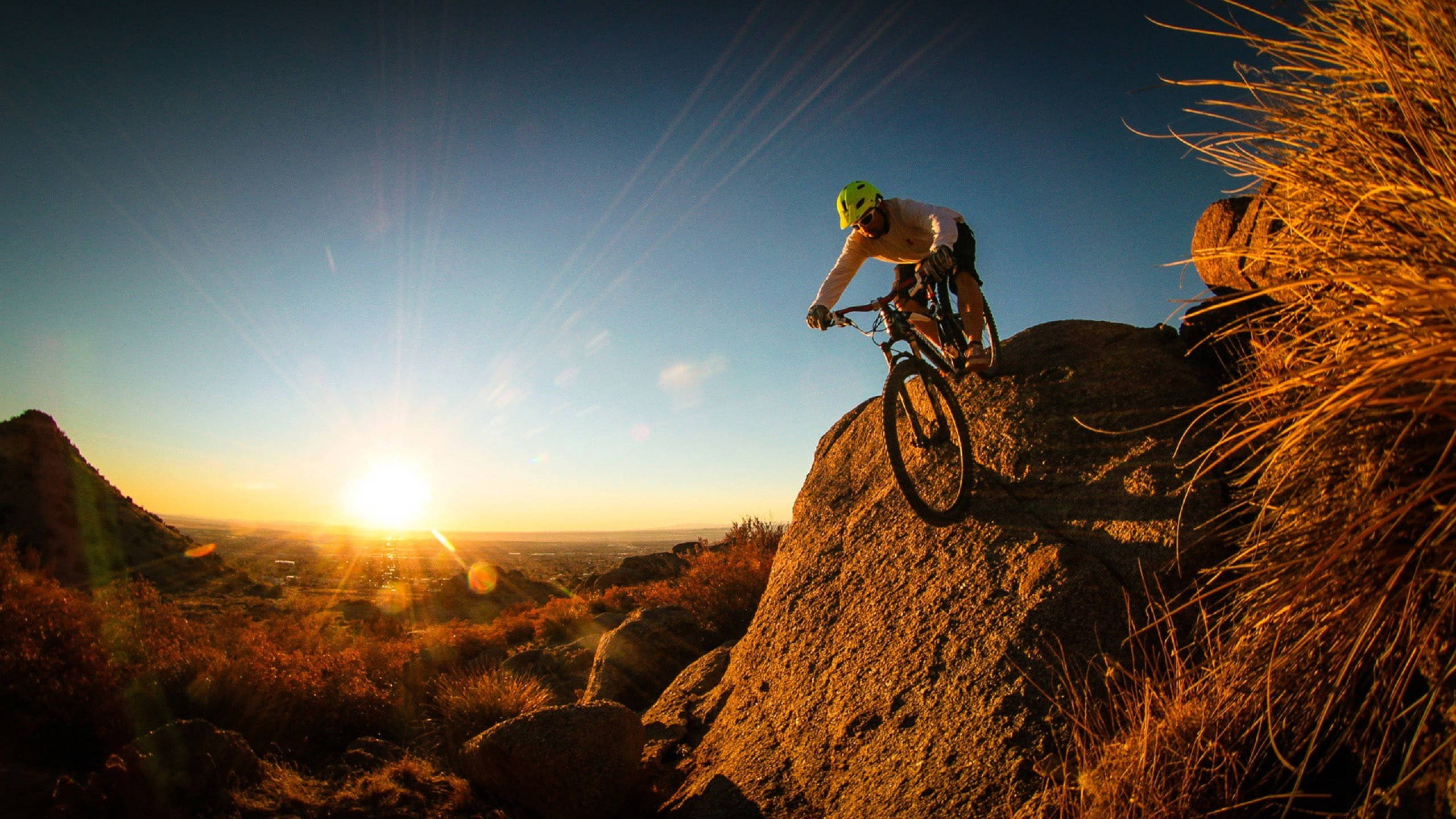 neon helmet, rocky trail, sun sets behind him, 2K Desktop Wallpaper