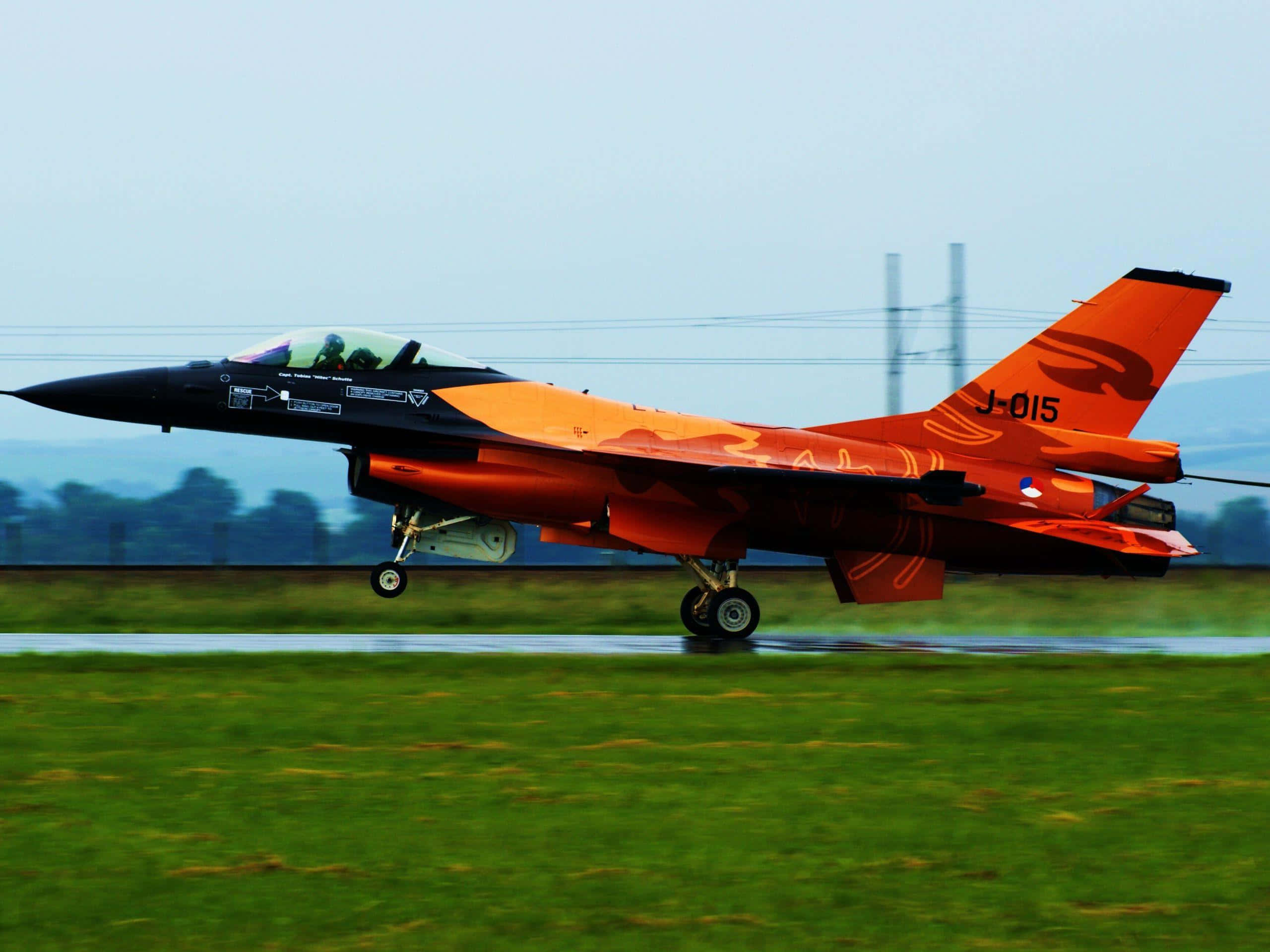 orange F16 fighter jet, wet runway, blurred green grass, 2K Desktop Wallpaper