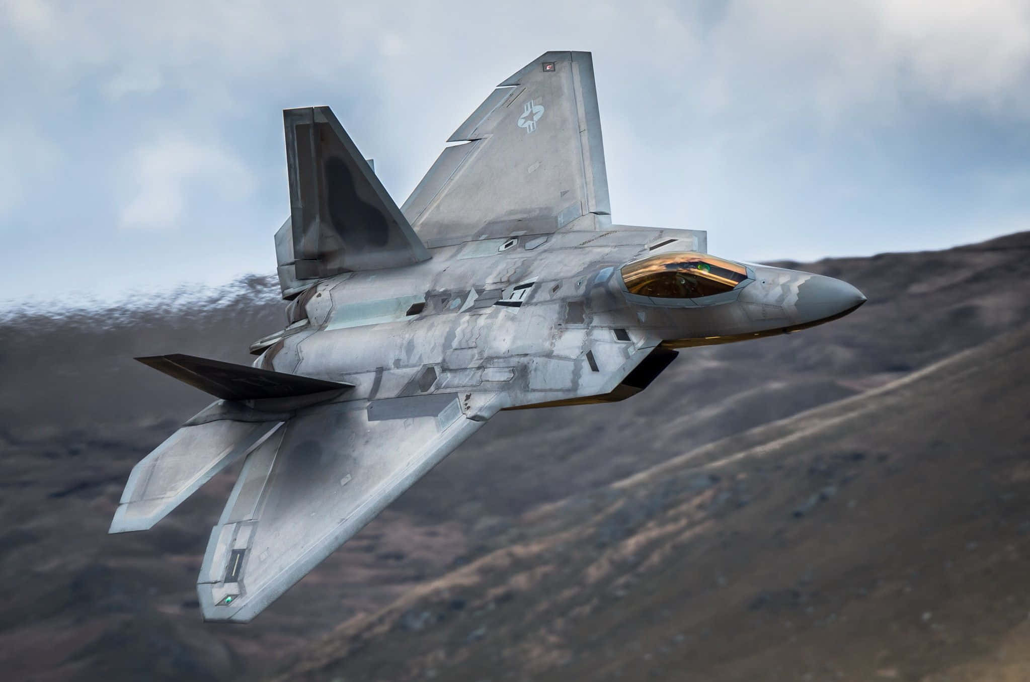 F-22 Raptor, sleek gray fighter jet, rugged mountain terrain, Full HD Desktop Wallpaper