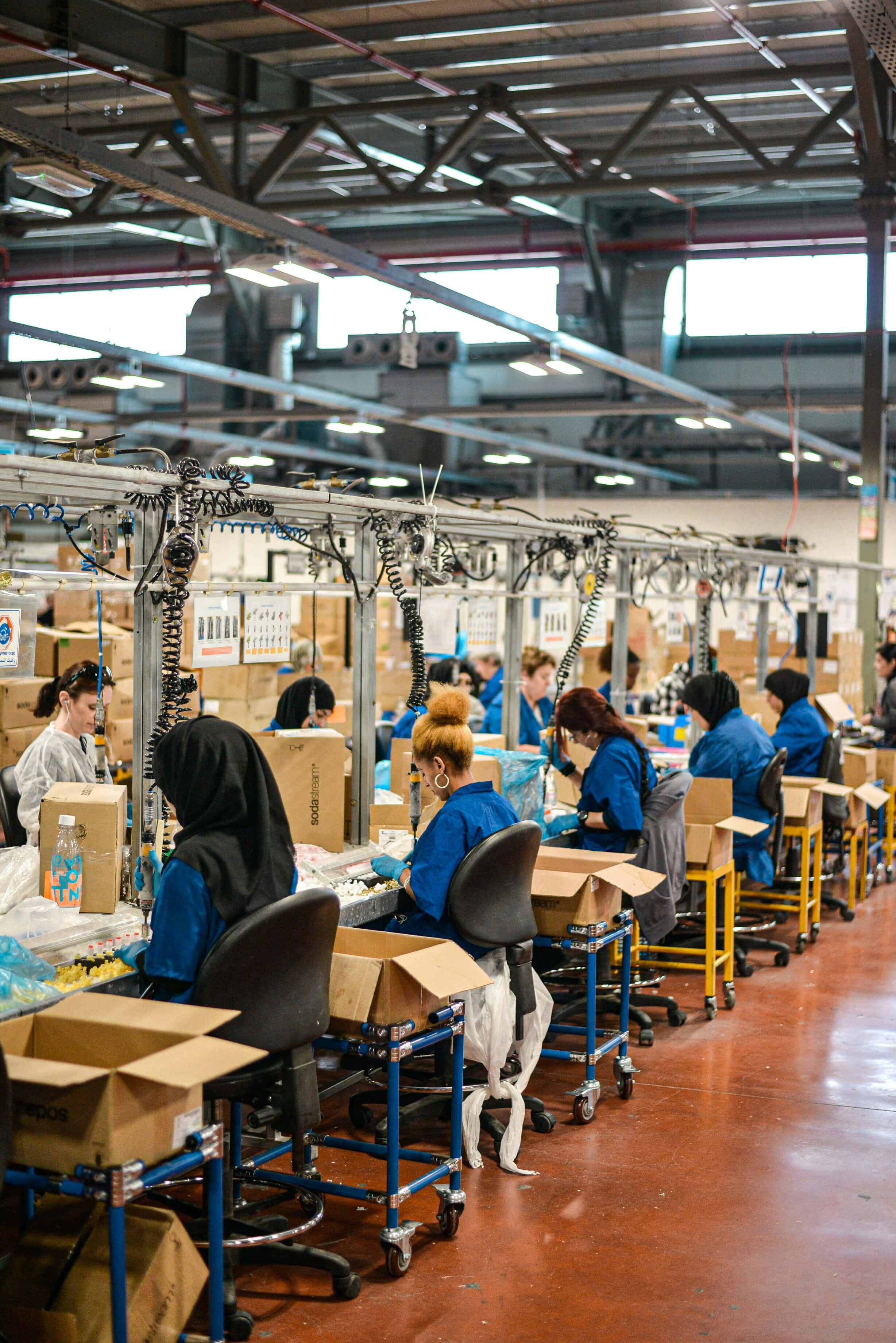industrial assembly line, blue uniforms, bright overhead lights, 2K Phone Wallpaper