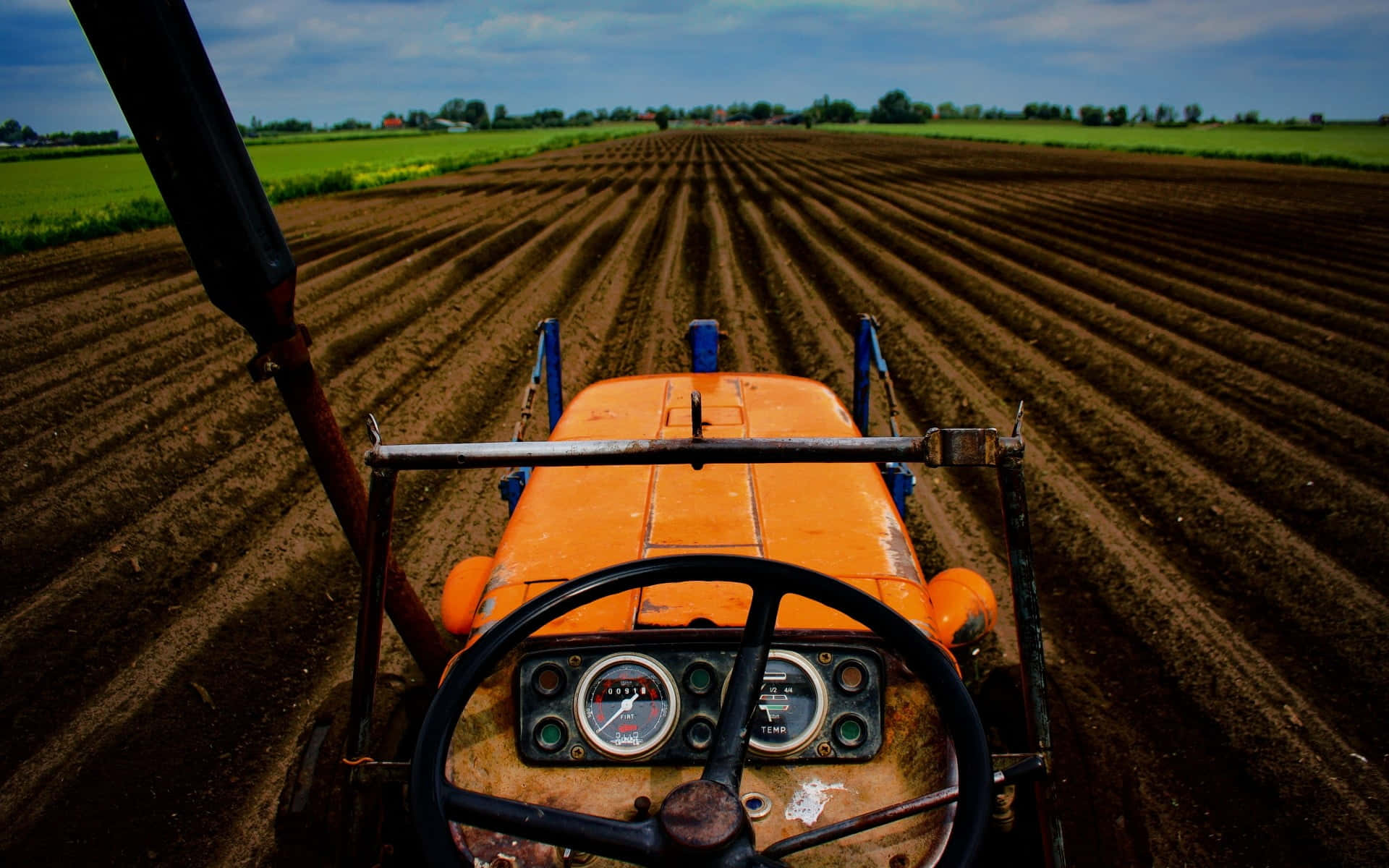 orange tractor, freshly tilled brown soil rows, cloudy sky, Full HD Desktop Wallpaper