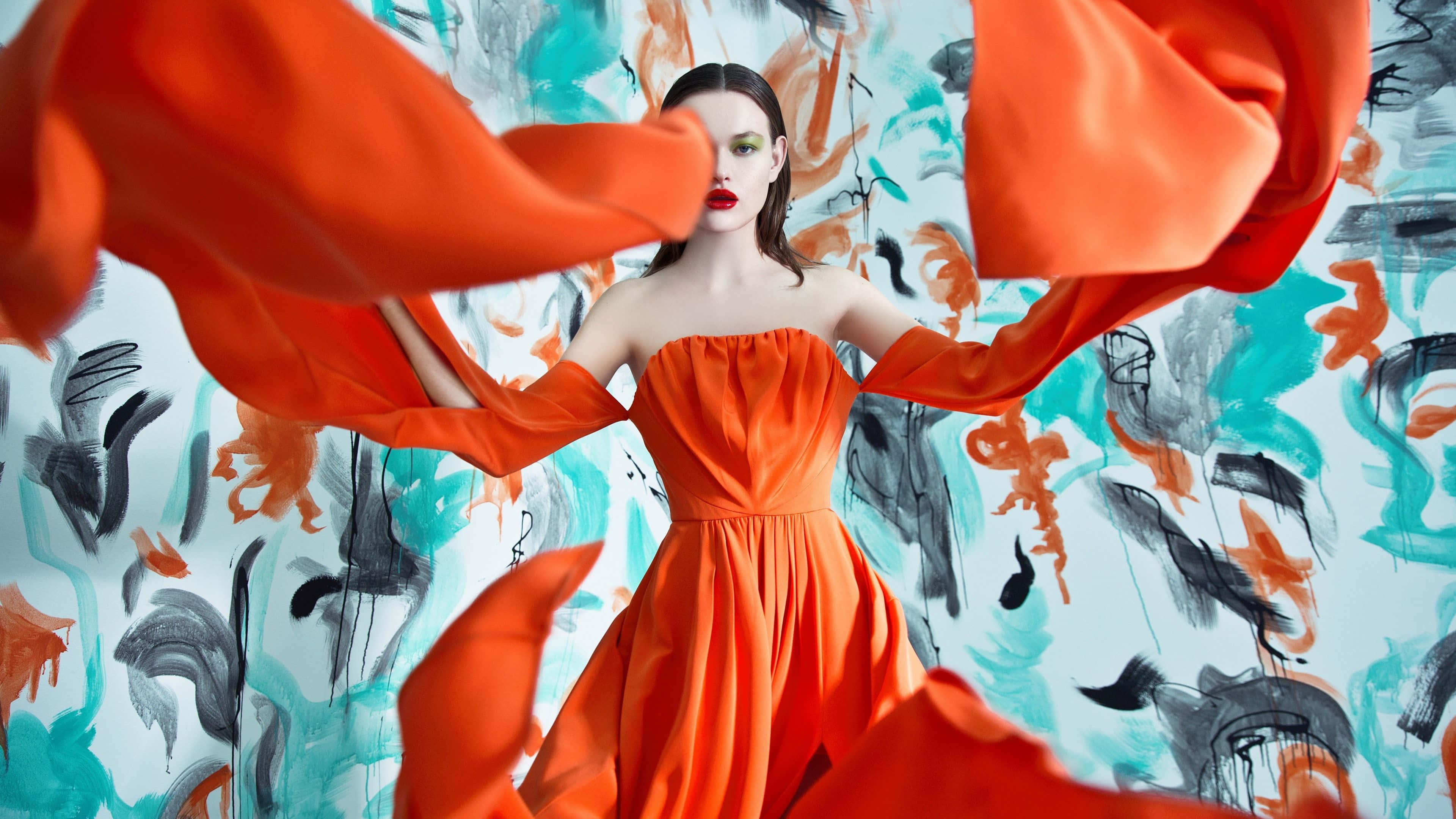 vibrant orange strapless gown, flowing sleeves, bold abstract wall, 4K Desktop Wallpaper