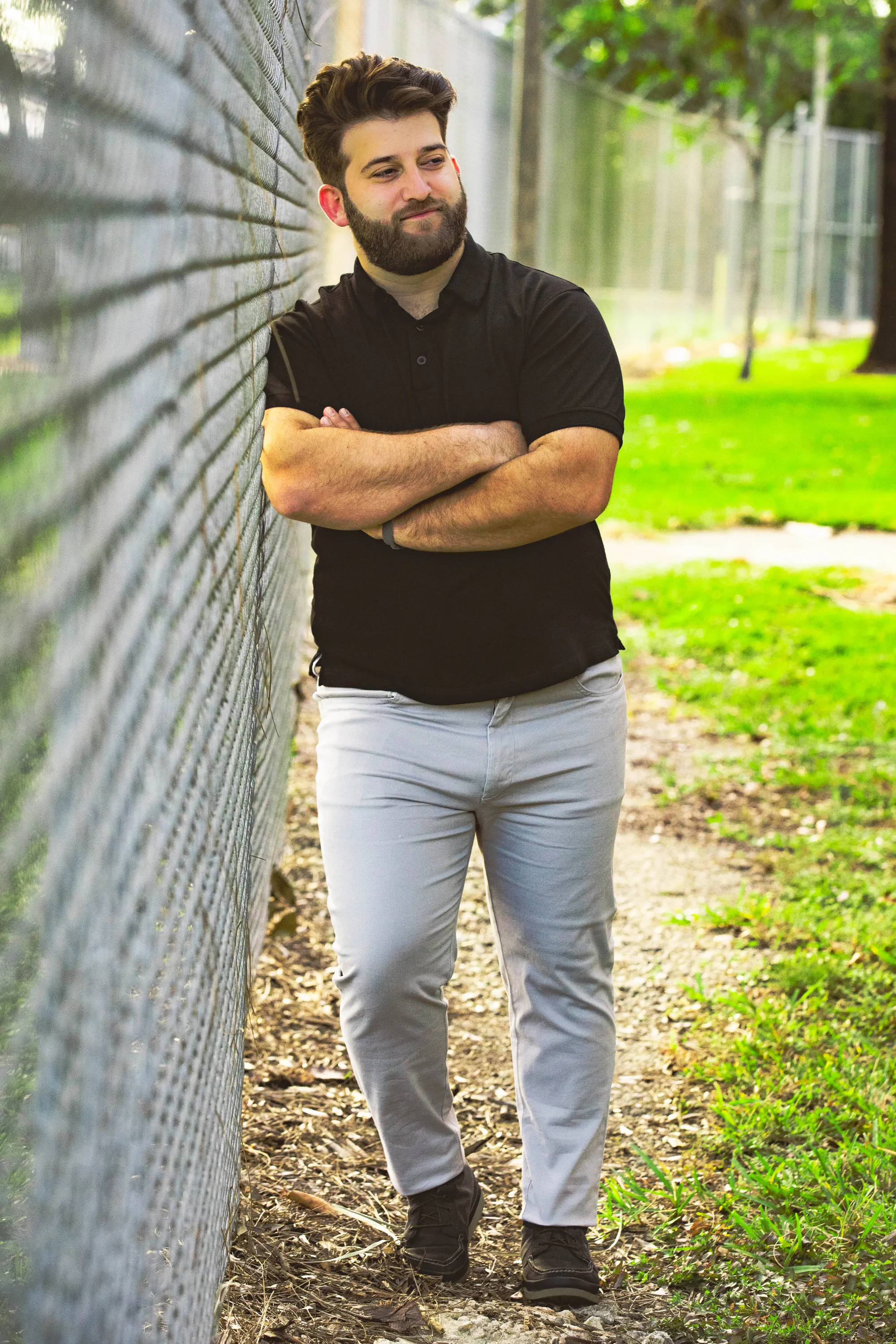 bearded man, black polo shirt, chain-link fence, 2K Phone Wallpaper