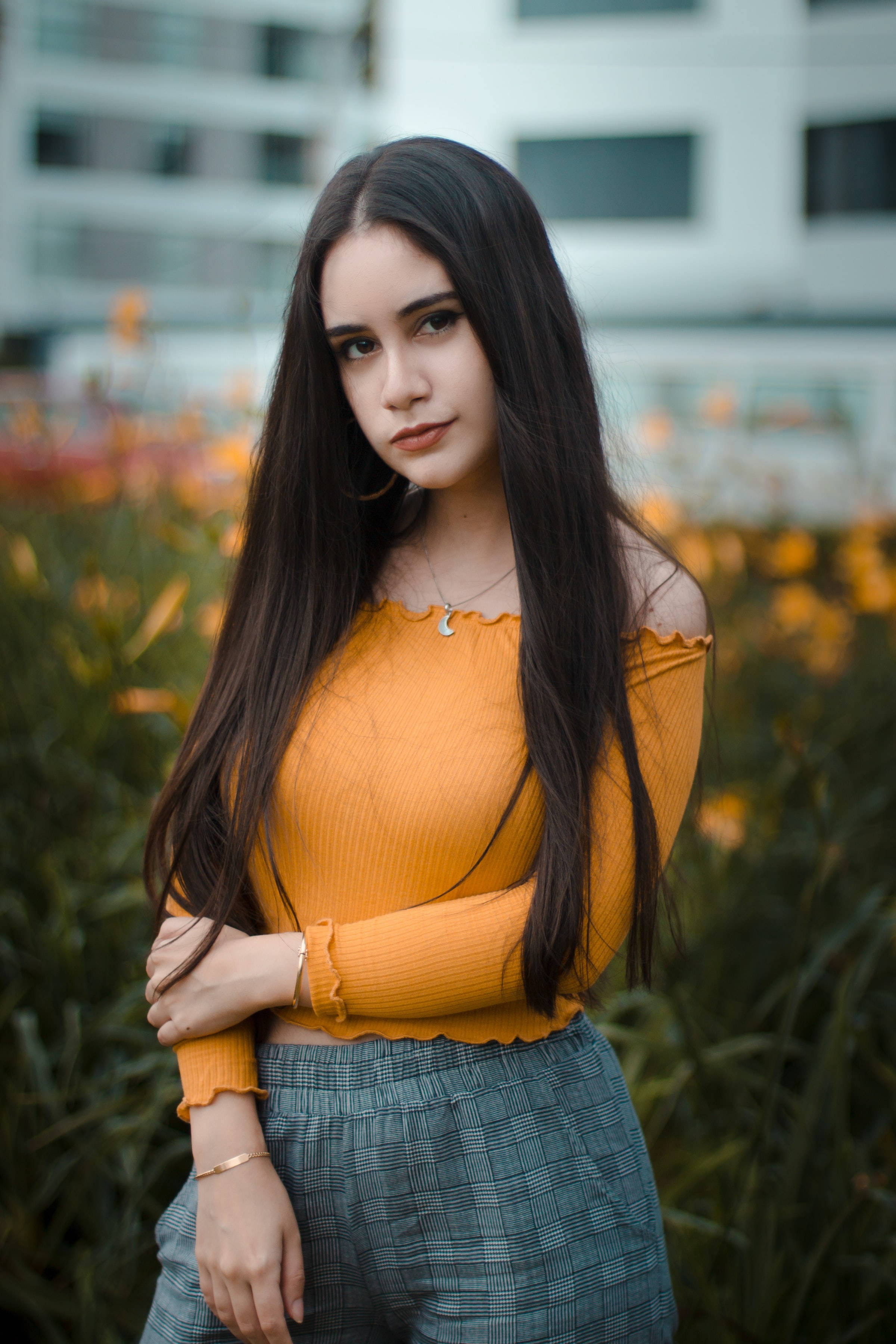 female model, long dark hair, vibrant orange top, 2K Phone Wallpaper