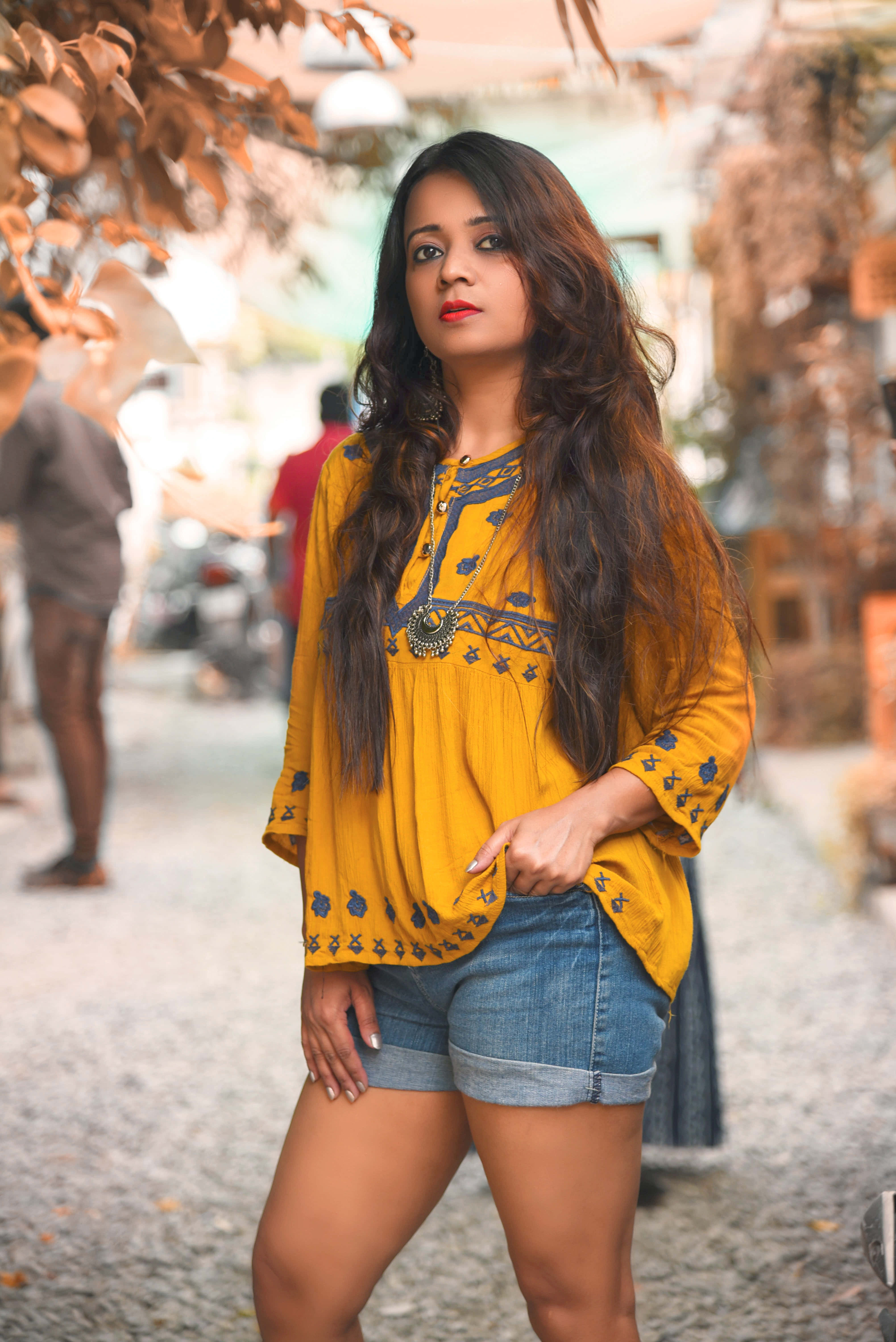 vibrant yellow embroidered top, denim shorts, sunlit cobblestone street, 5K Phone Wallpaper