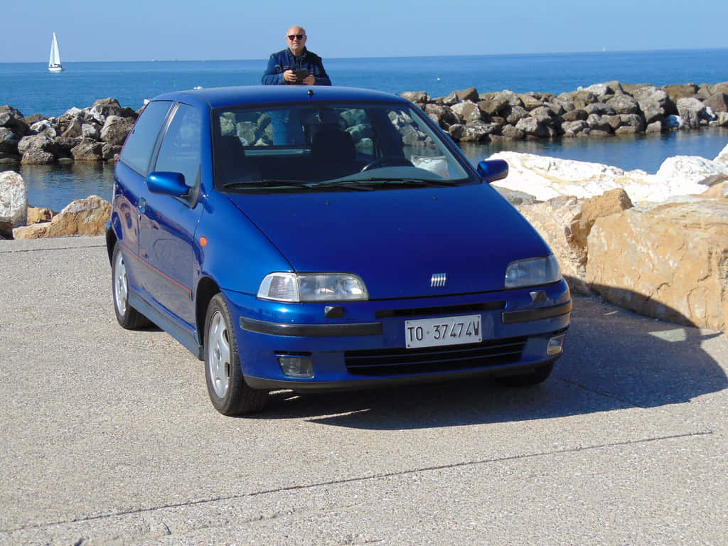 Fiat Punto, vibrant blue, sunlit coastal road, SD Desktop Wallpaper
