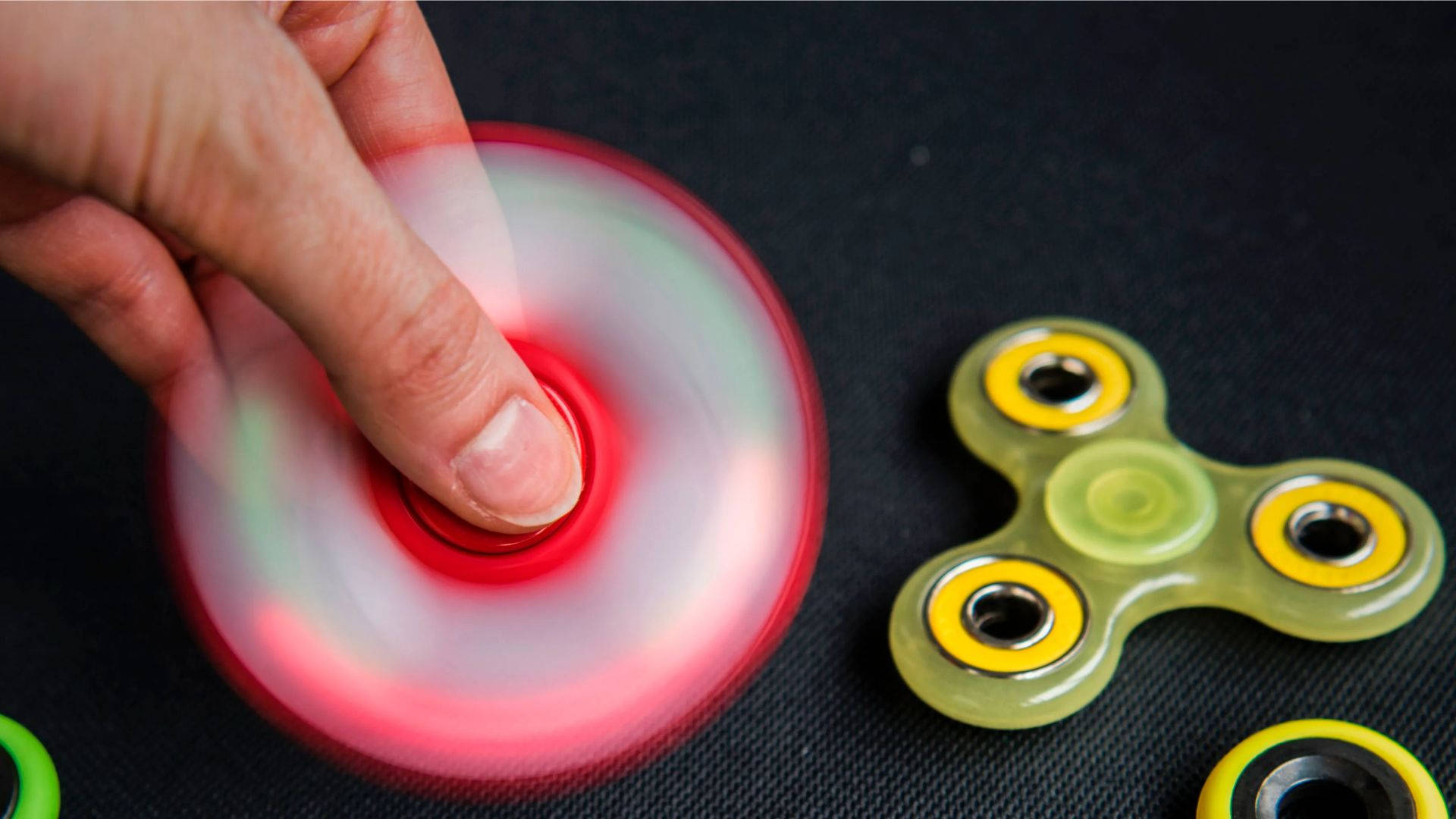 spinning red fidget toy, glowing red fidget spinner, dark textured surface, Full HD Desktop Wallpaper