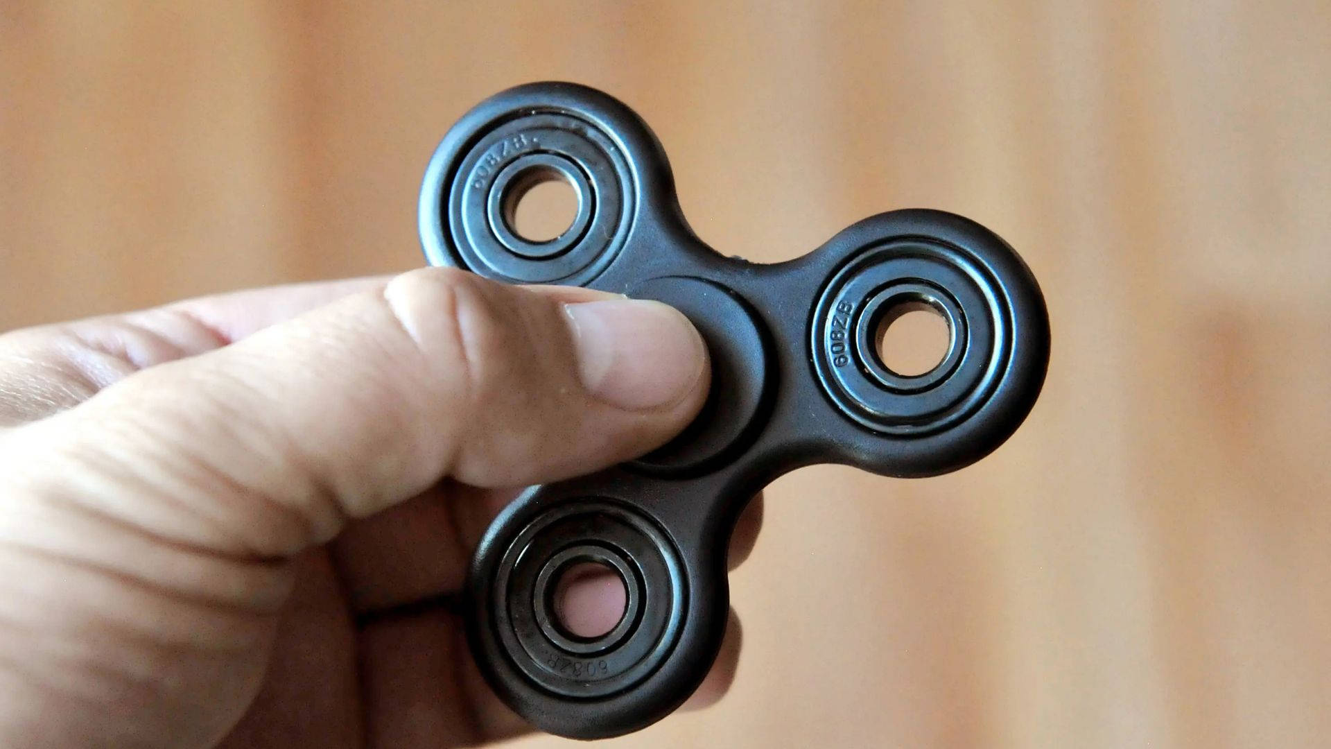black fidget spinner, warm wooden background, soft focus, Full HD Desktop Wallpaper