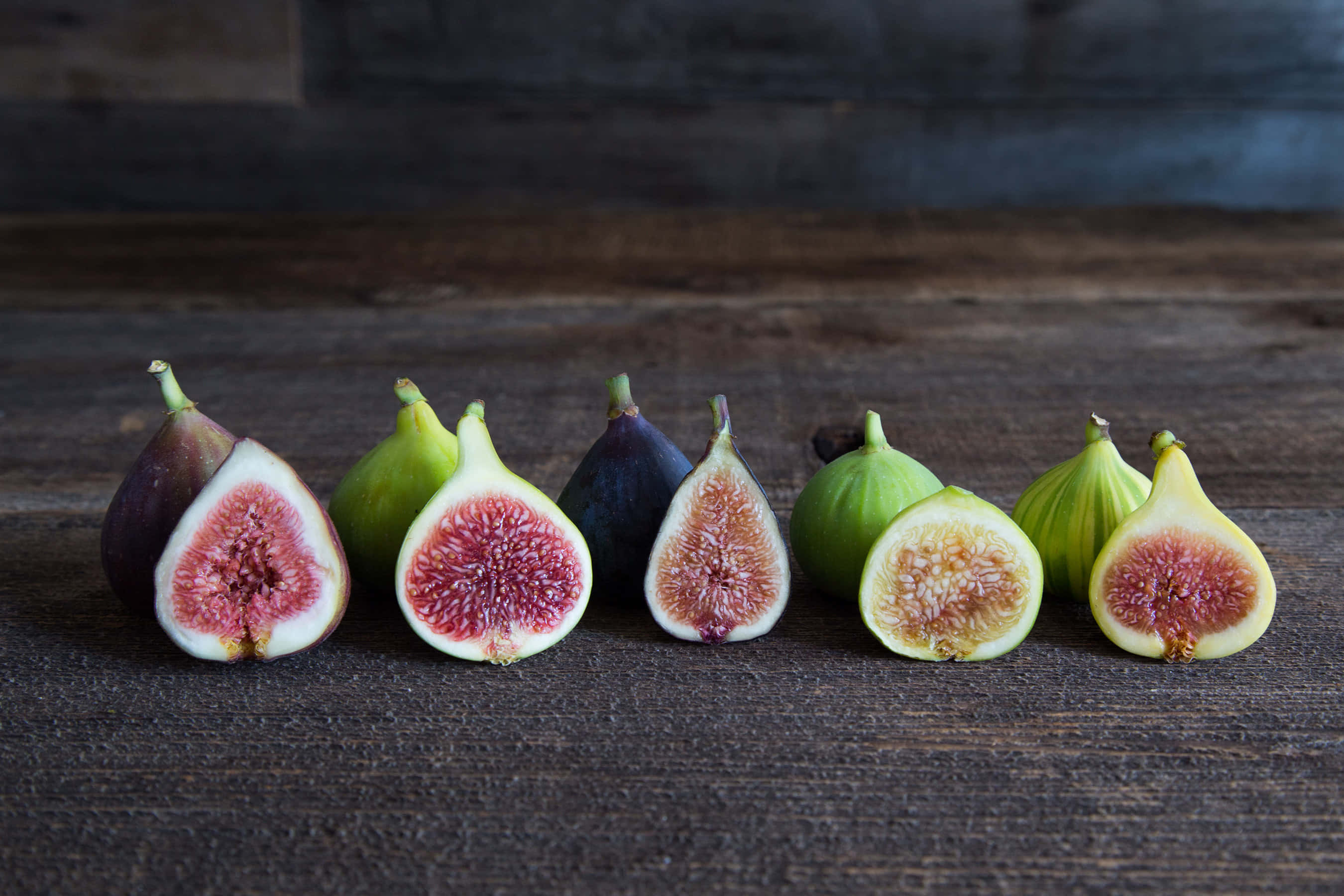 fresh figs, pinkish red interiors, dark wooden surface, 2K Desktop Wallpaper
