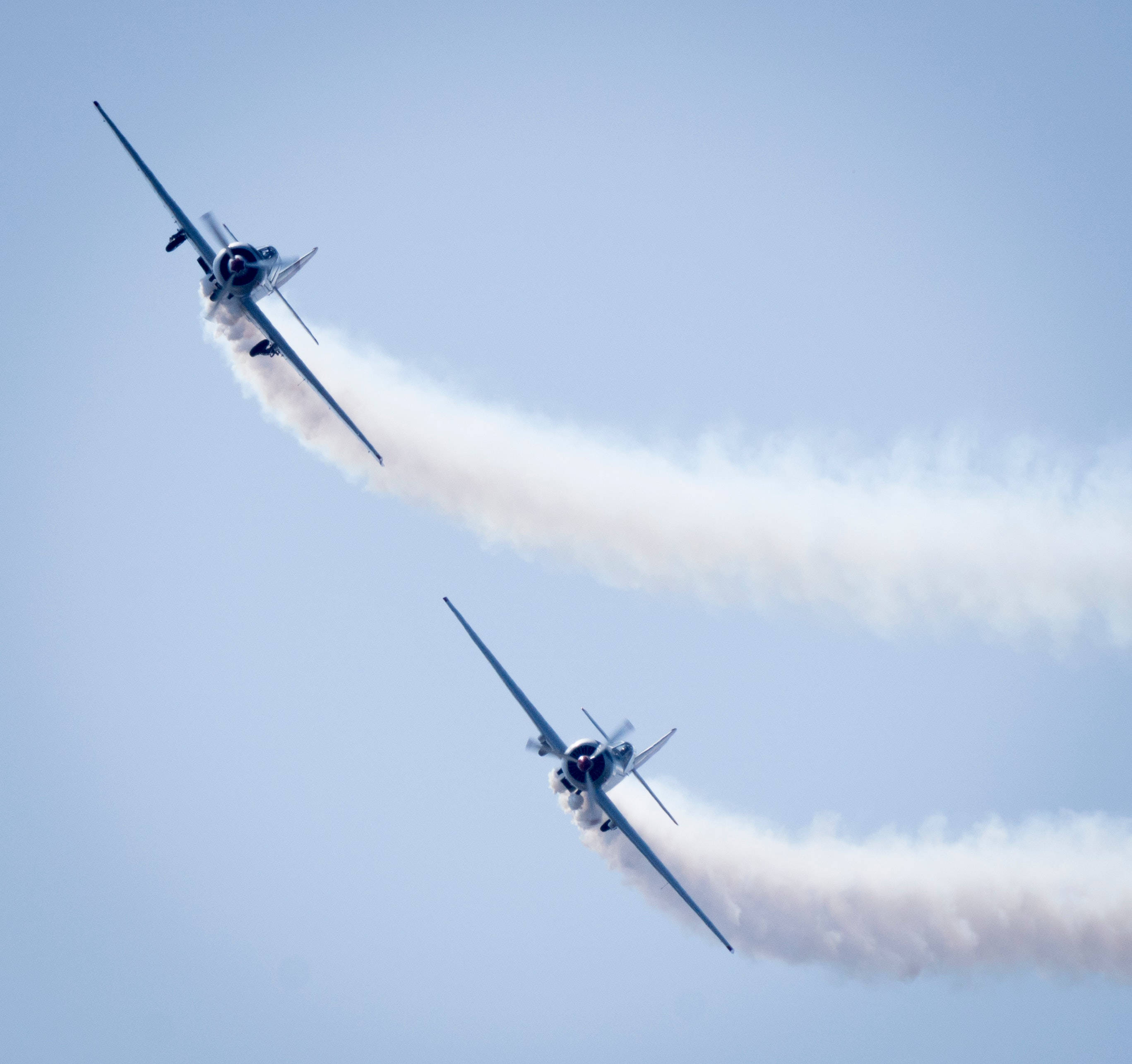vintage propeller planes, clear blue sky, thick white smoke trails, 2K Desktop Wallpaper