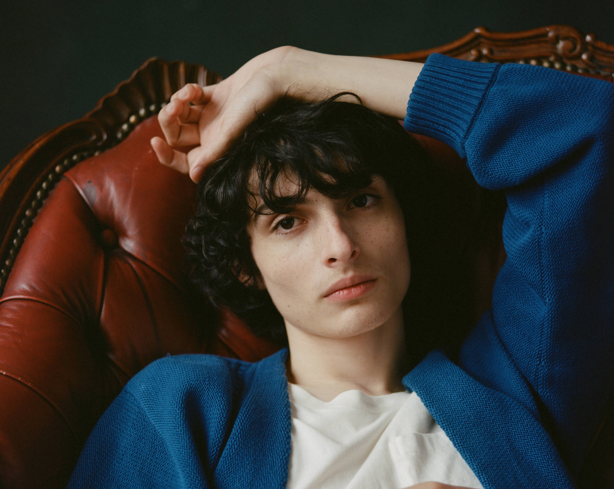 Finn Wolfhard, blue jacket, vintage red leather chair, 2K Desktop Wallpaper