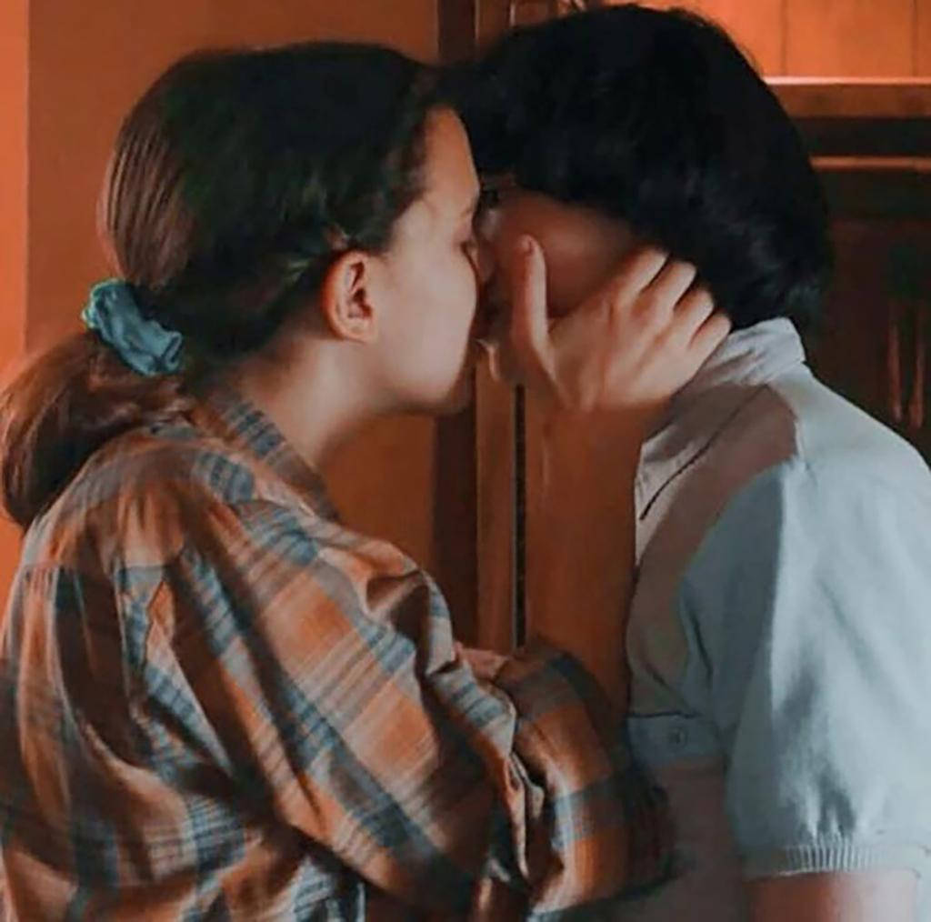 Finn Wolfhard, kissing scene, warmly lit indoor setting, SD Desktop Wallpaper
