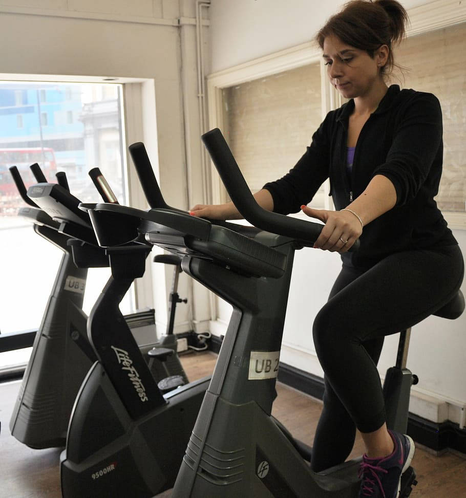 upright exercise bike, black workout gear, bright gym, SD Phone Wallpaper
