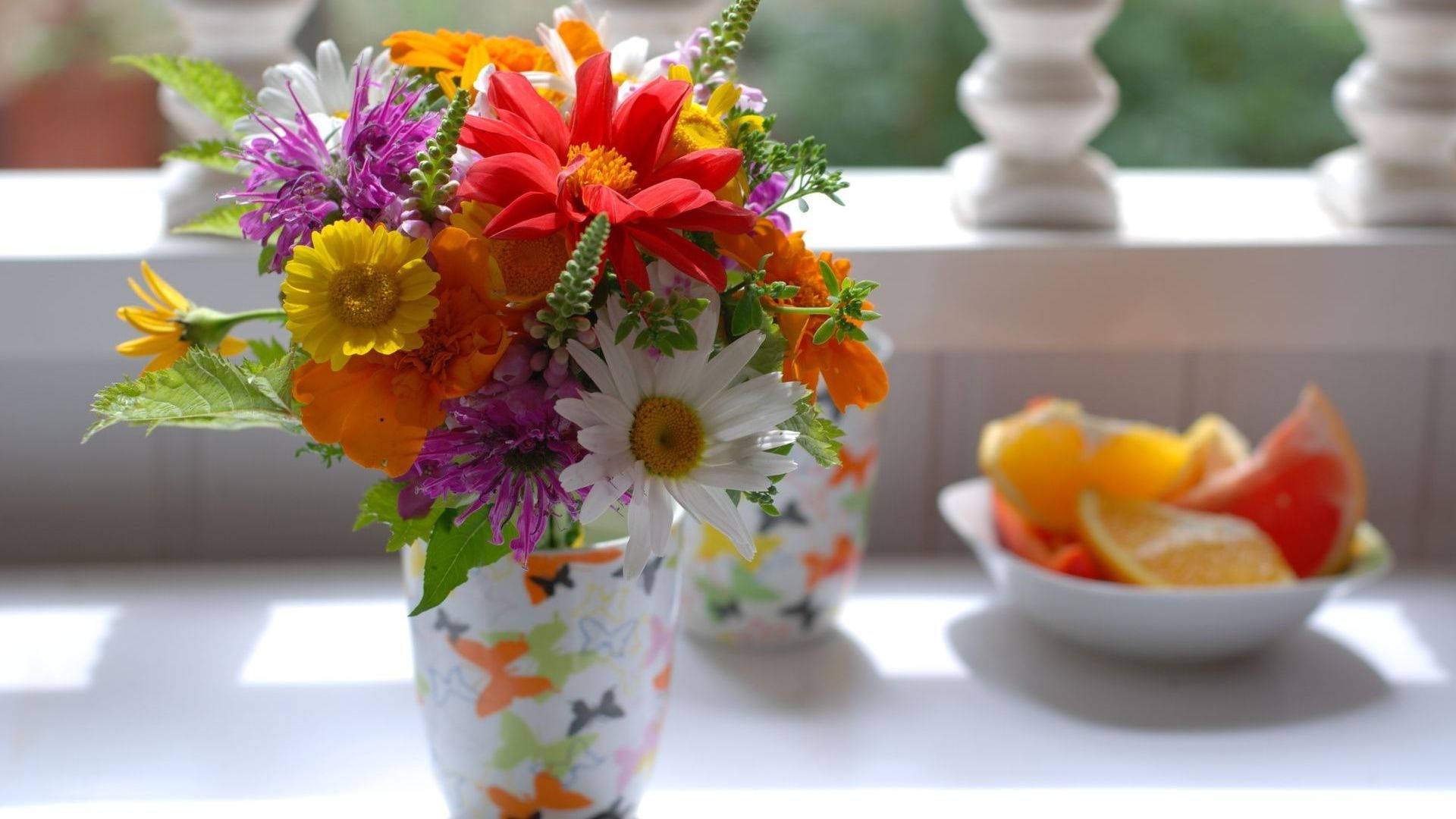butterfly-patterned vase, red yellow and purple flowers, bowl of citrus slices, Full HD Desktop Wallpaper