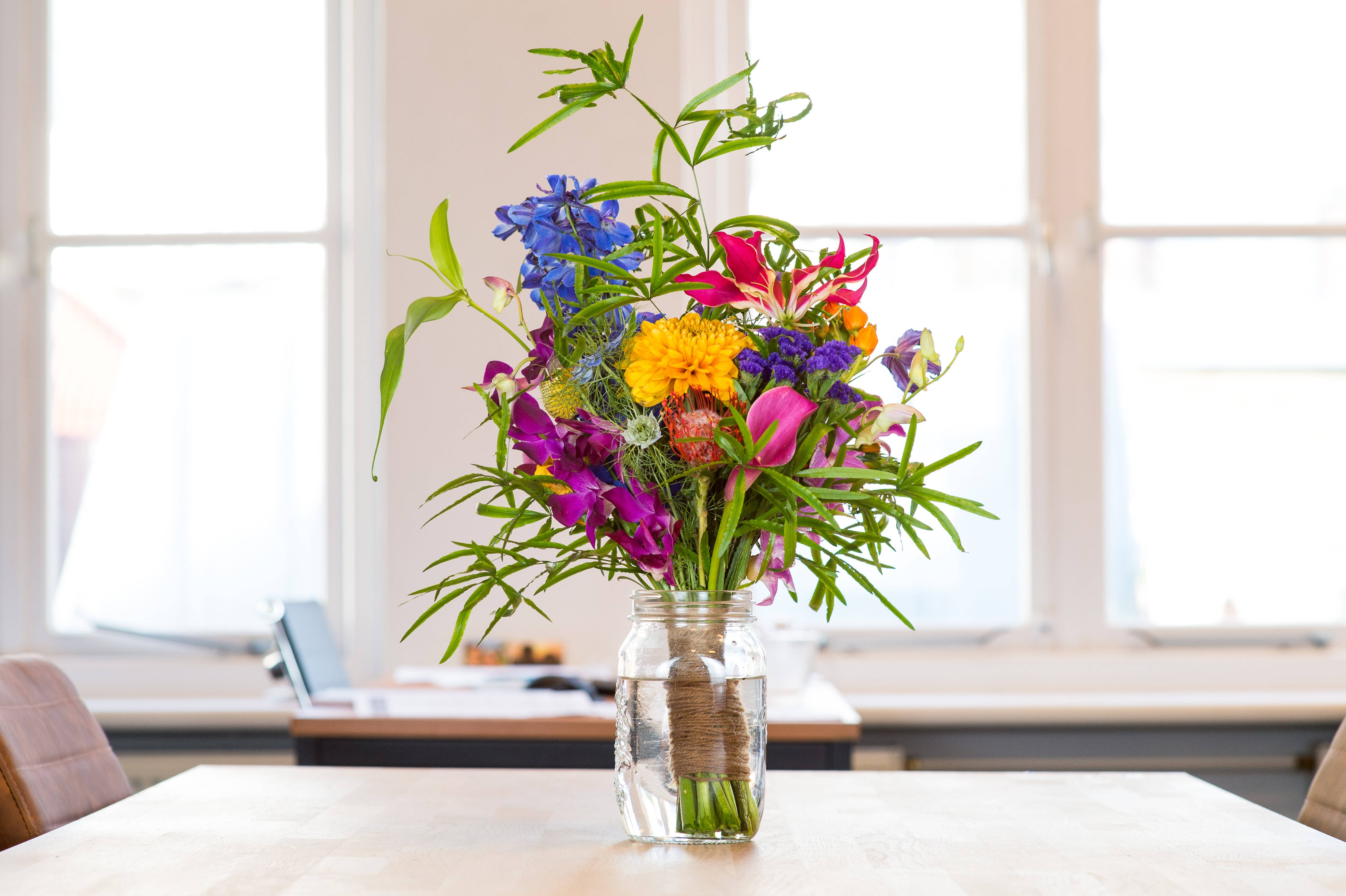 dining table, bouquet of blue pink yellow and purple flowers, glass jar, 4K Desktop Wallpaper